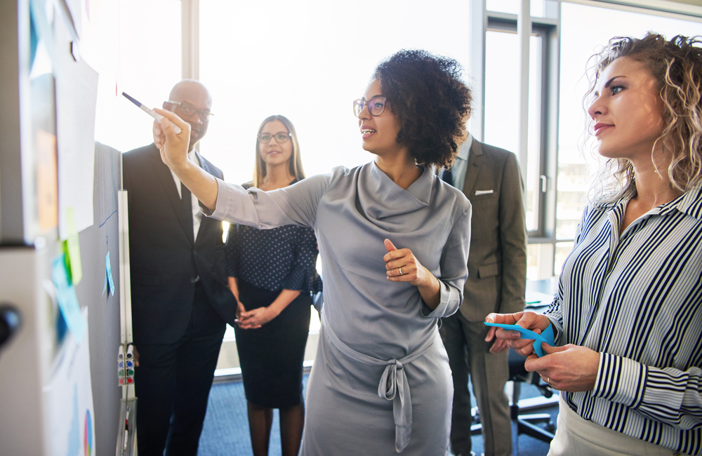 A group of office workers looking at a whiteboard. 