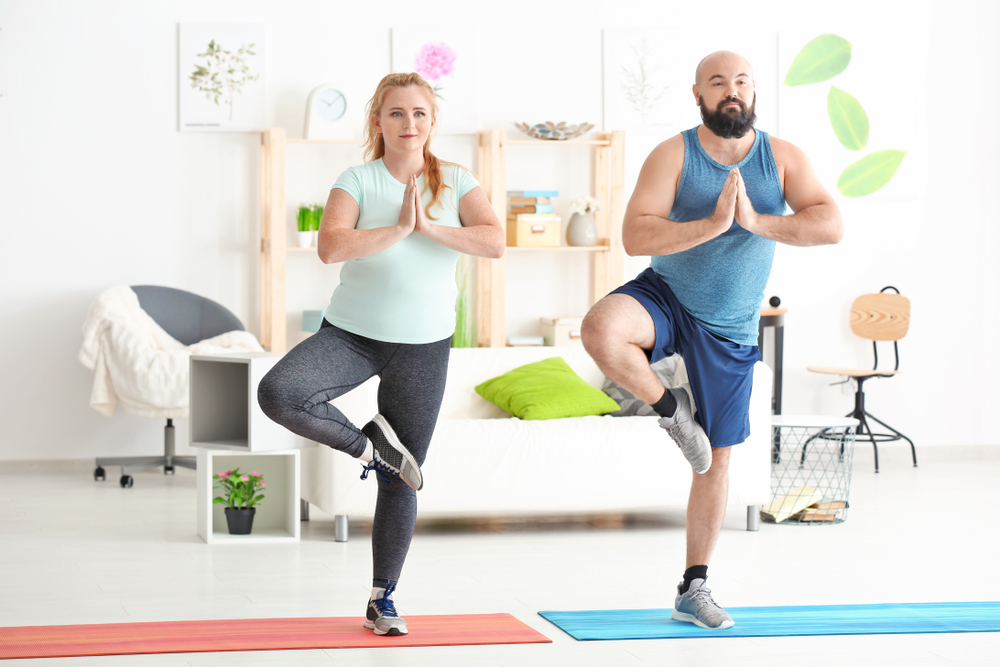 Un homme et une femme font du yoga dans un salon.