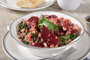 Un bol de salade de quinoa posé sur une assiette.