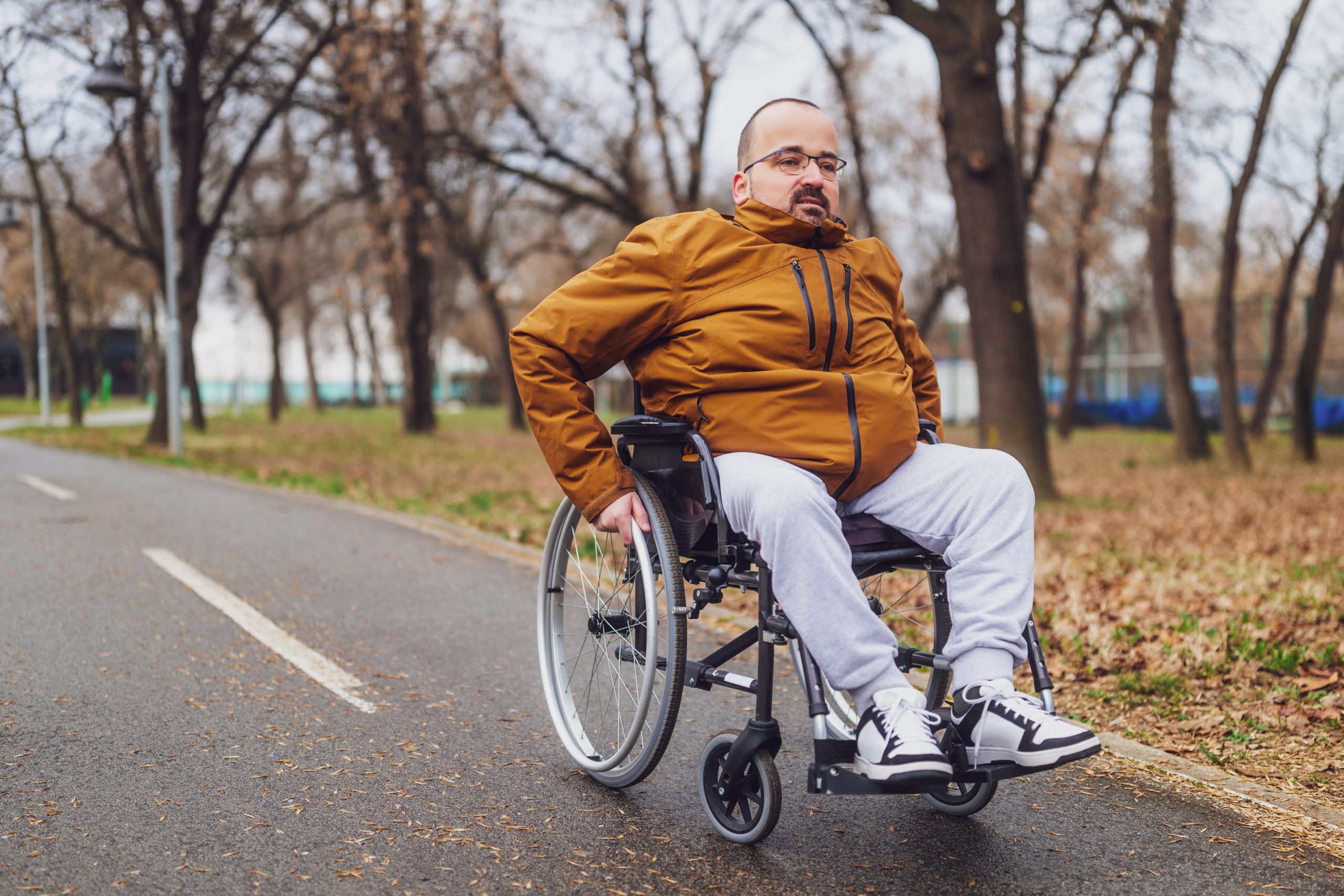 Un homme en fauteuil roulant sur un chemin de parc. Un homme en fauteuil roulant sur un chemin de parc.