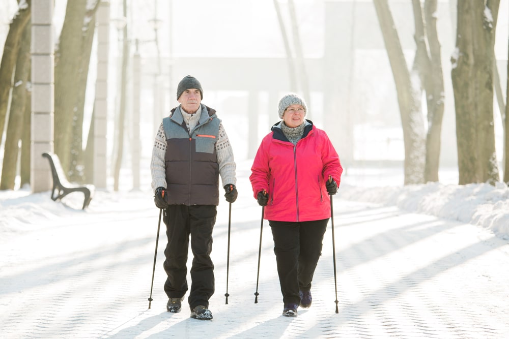 Un homme et une femme marchent en utilisant des bâtons de ski sur un sentier enneigé. Un homme et une femme marchent en utilisant des bâtons de ski sur un sentier enneigé.
