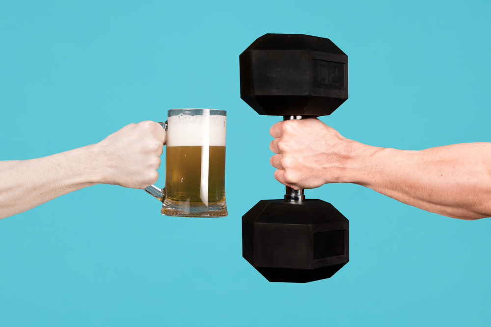 Une main tient une chope de bière et une autre tient un haltère. Une main tient une chope de bière et une autre tient un haltère.