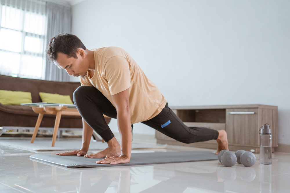 A man doing a lunges in a living room. A man doing a lunges in a living room.
