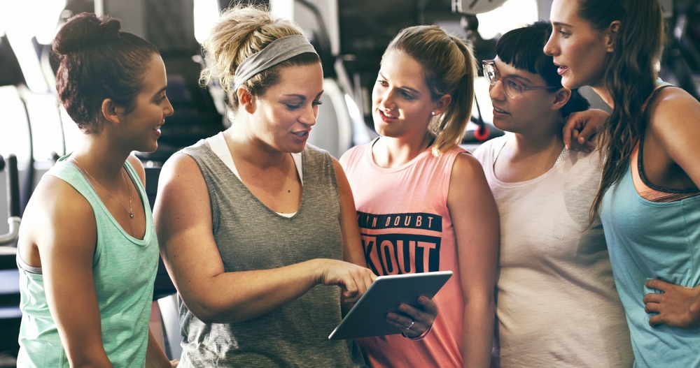Un groupe de femmes dans un gymnase regardant une tablette. Un groupe de femmes dans un gymnase regardant une tablette.