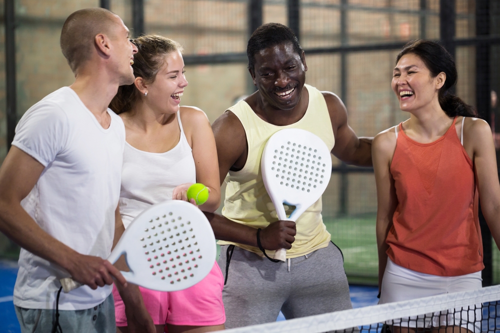 Un groupe de personnes souriantes tenant des raquettes et des balles de tennis léger. Un groupe de personnes souriantes tenant des raquettes et des balles de tennis léger.