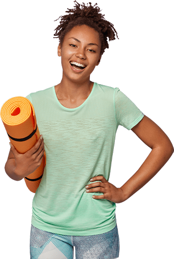 A woman smiling and holding an orange yoga mat