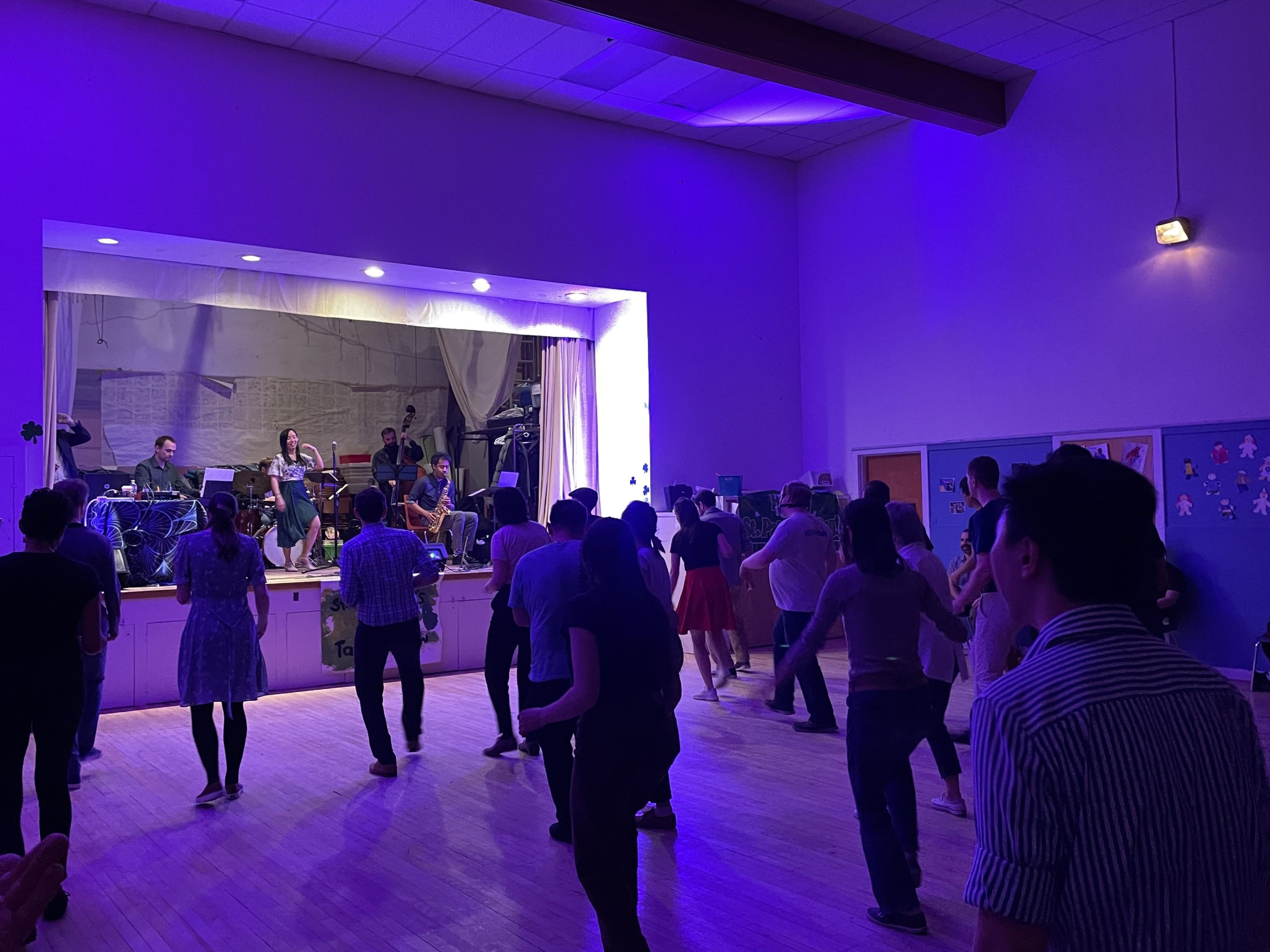 People dancing in a hall with a live band performing on stage. People dancing in a hall with a live band performing on stage.