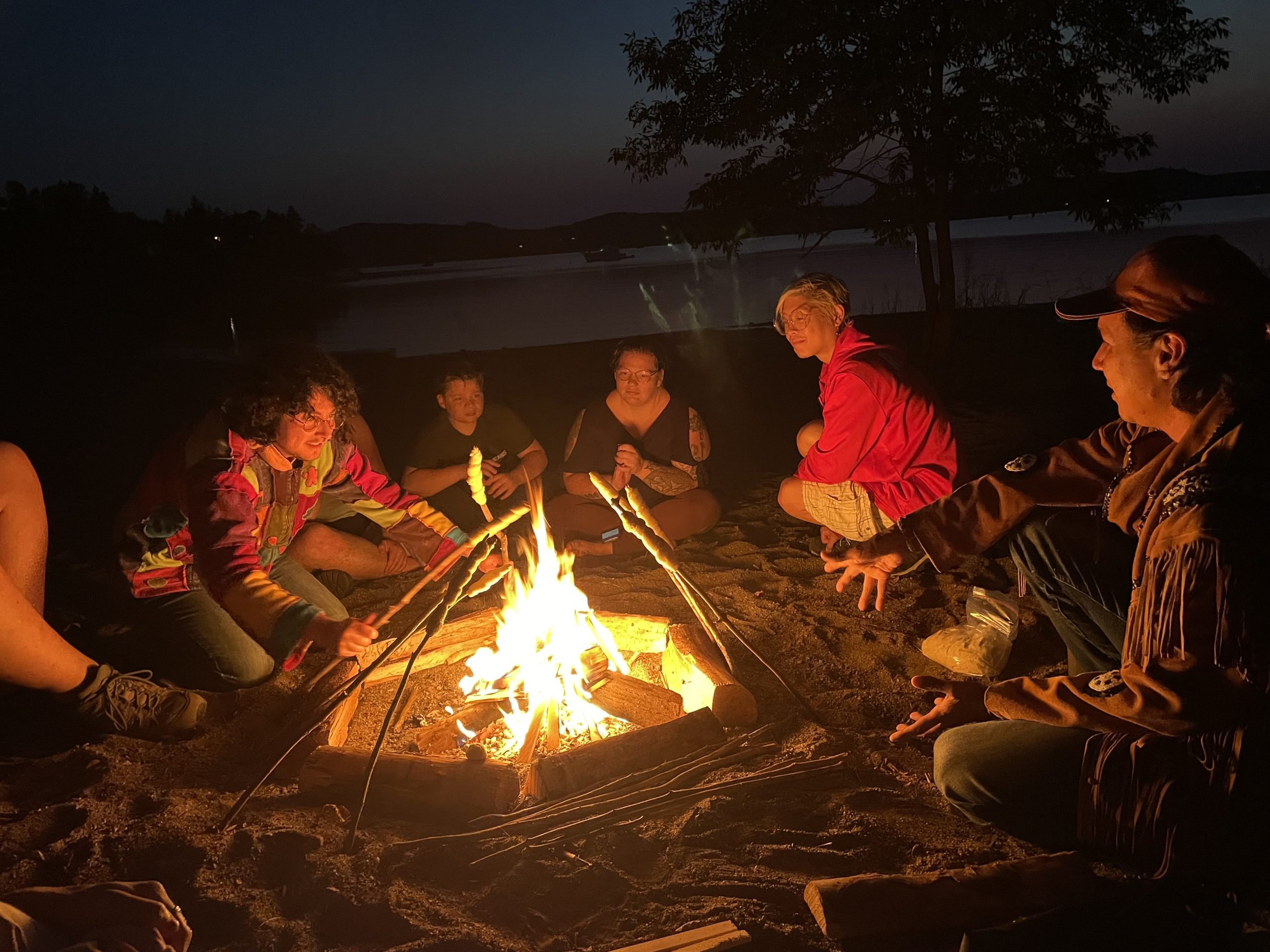 Un groupe de personnes autour d’un feu de plage au coucher du soleil. Un groupe de personnes autour d’un feu de plage au coucher du soleil.