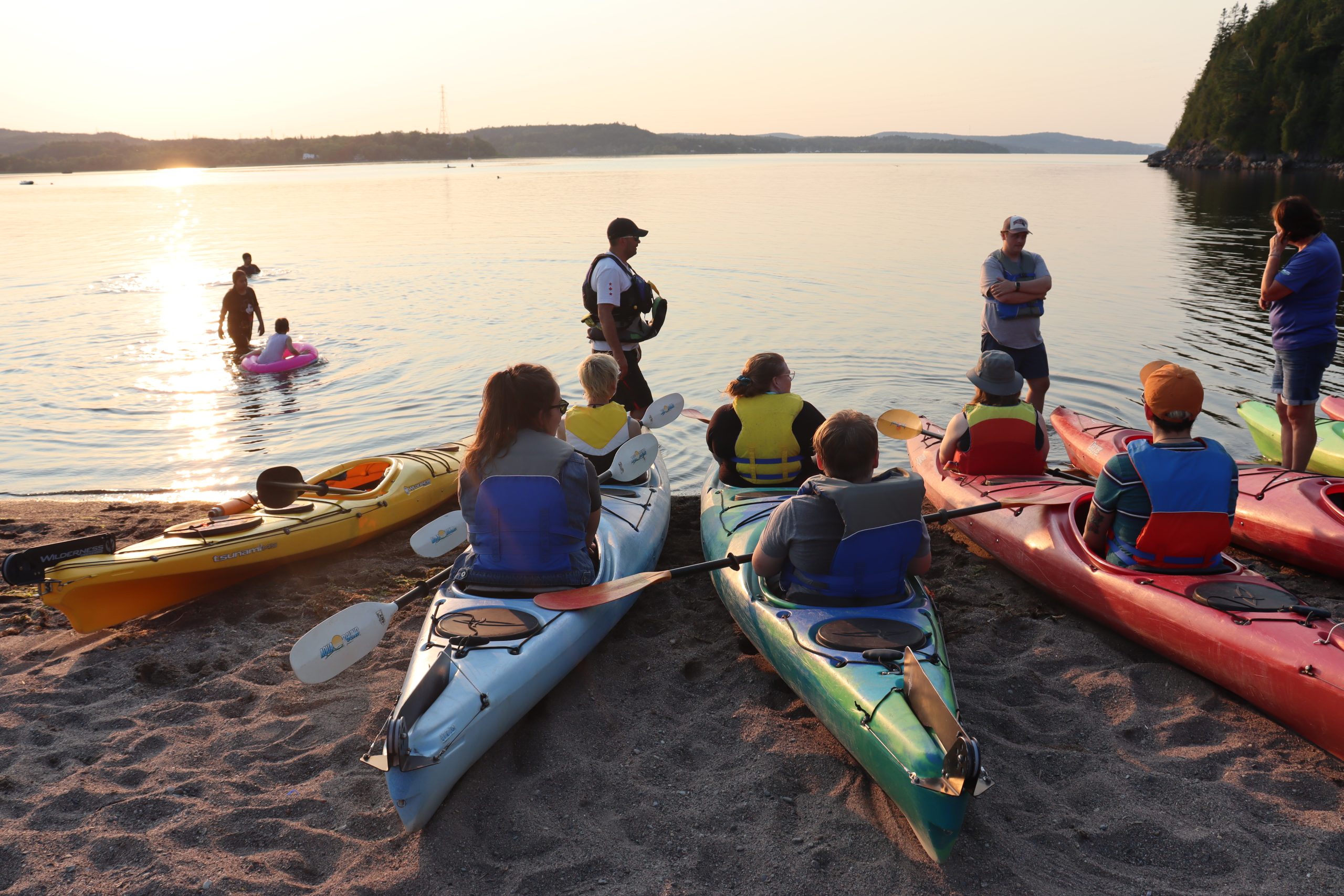 Un groupe de personnes assises dans des kayaks sur une plage. Un groupe de personnes assises dans des kayaks sur une plage.