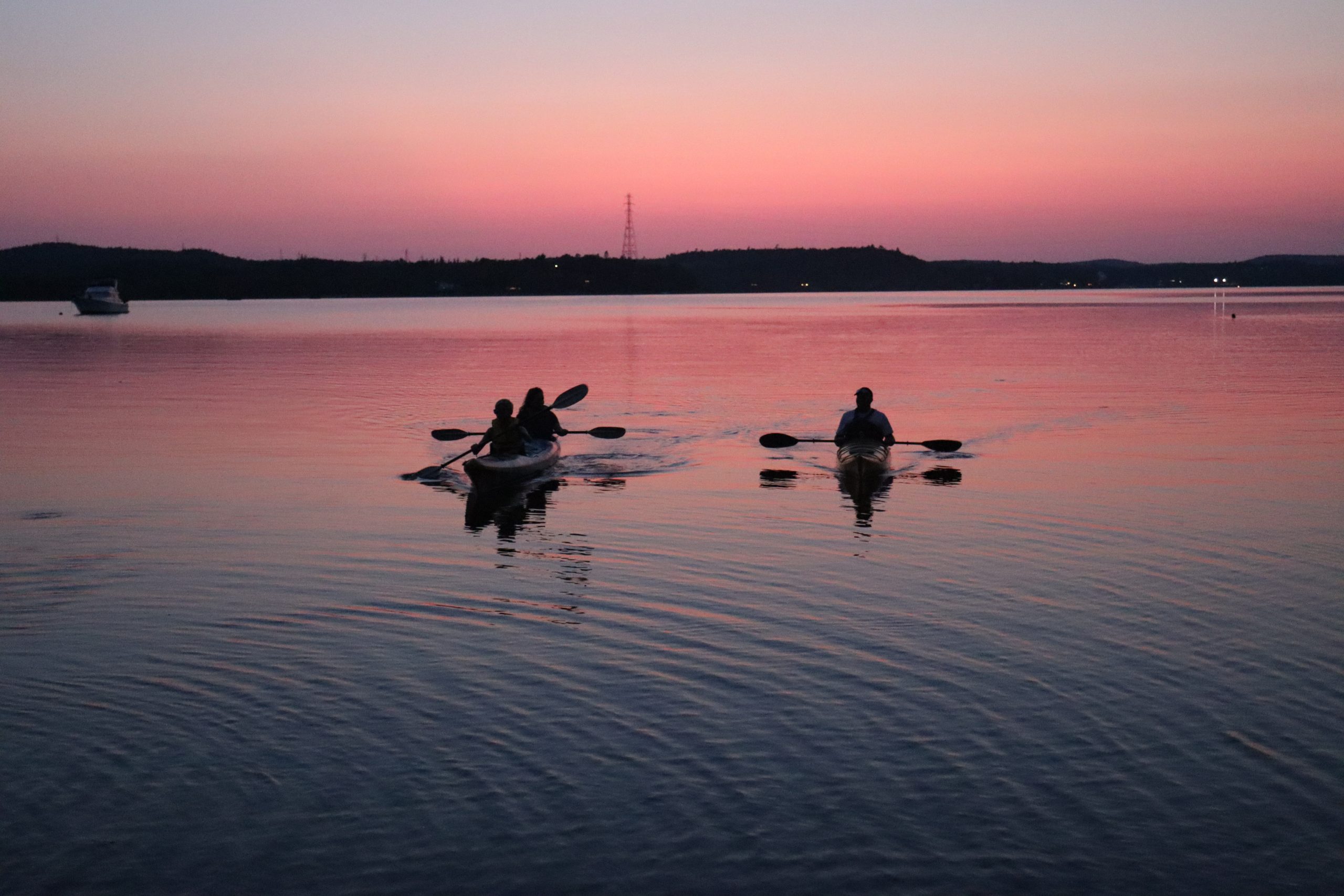 Un groupe de personnes faisant du kayak sur la rivière Wolastoq/Saint John au coucher du soleil. Un groupe de personnes faisant du kayak sur la rivière Wolastoq/Saint John au coucher du soleil.