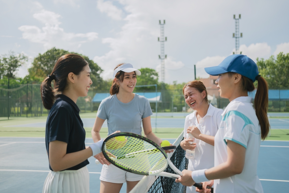 Un groupe de joueurs de tennis souriant et parlant sur un court extérieur. Un groupe de joueurs de tennis souriant et parlant sur un court extérieur.