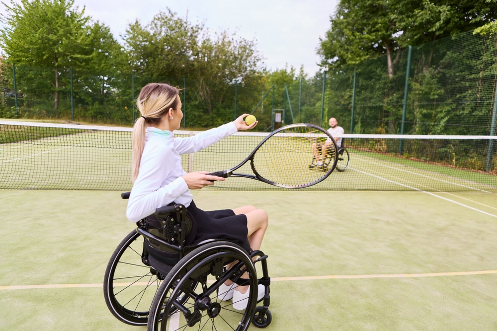 Deux personnes jouant au tennis en fauteuil roulant sur un terrain extérieur. Deux personnes jouant au tennis en fauteuil roulant sur un terrain extérieur.