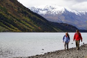 Deux personnes en randonnée au bord d’une rivière et d’une chaîne de montagnes.