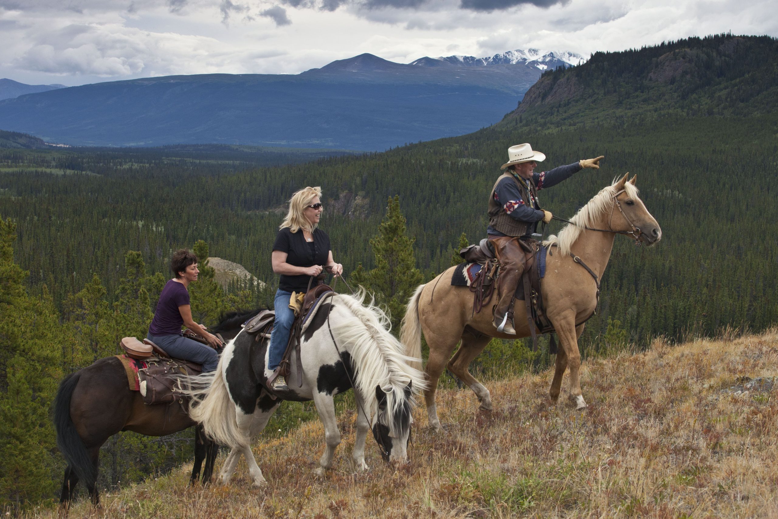 A group of people riding horses on a mountain. A group of people riding horses on a mountain.
