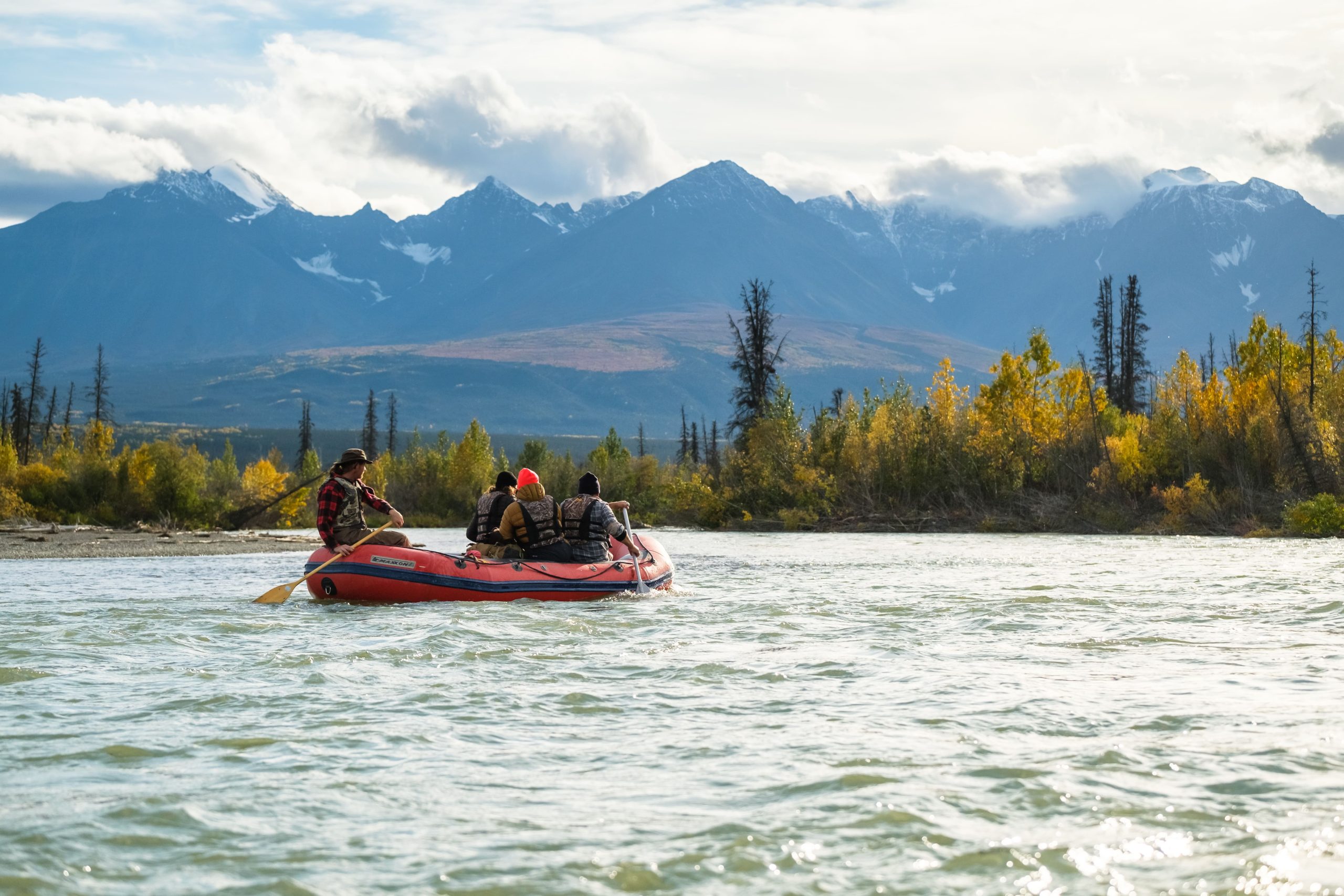 Un groupe de personnes faisant du rafting sur une rivière entourée d'arbres et de montagnes. Un groupe de personnes faisant du rafting sur une rivière entourée d'arbres et de montagnes.