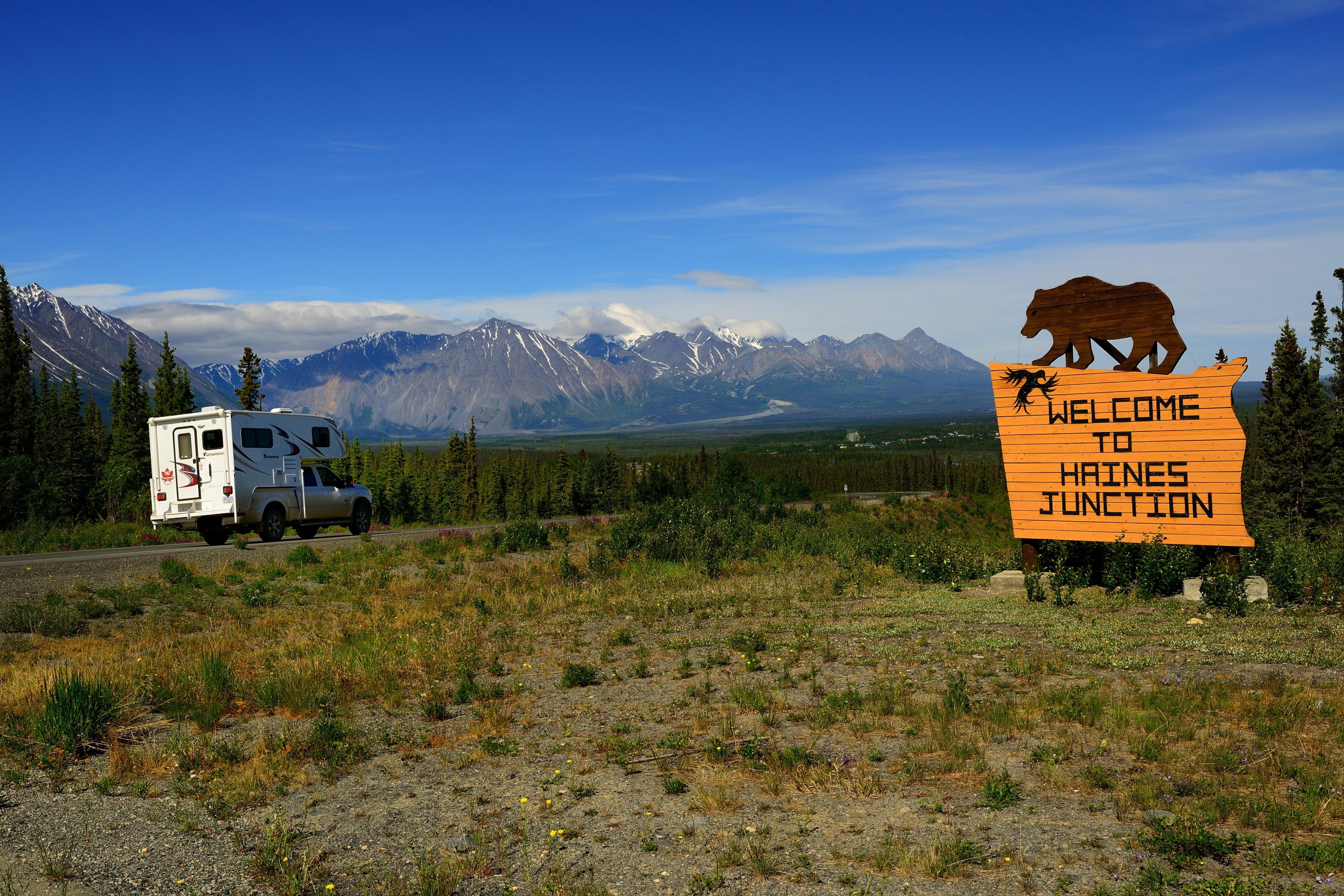 Un camping-car à côté d'un champ avec un panneau indiquant « Bienvenue à Haines Junction ». Un camping-car à côté d'un champ avec un panneau indiquant « Bienvenue à Haines Junction ».
