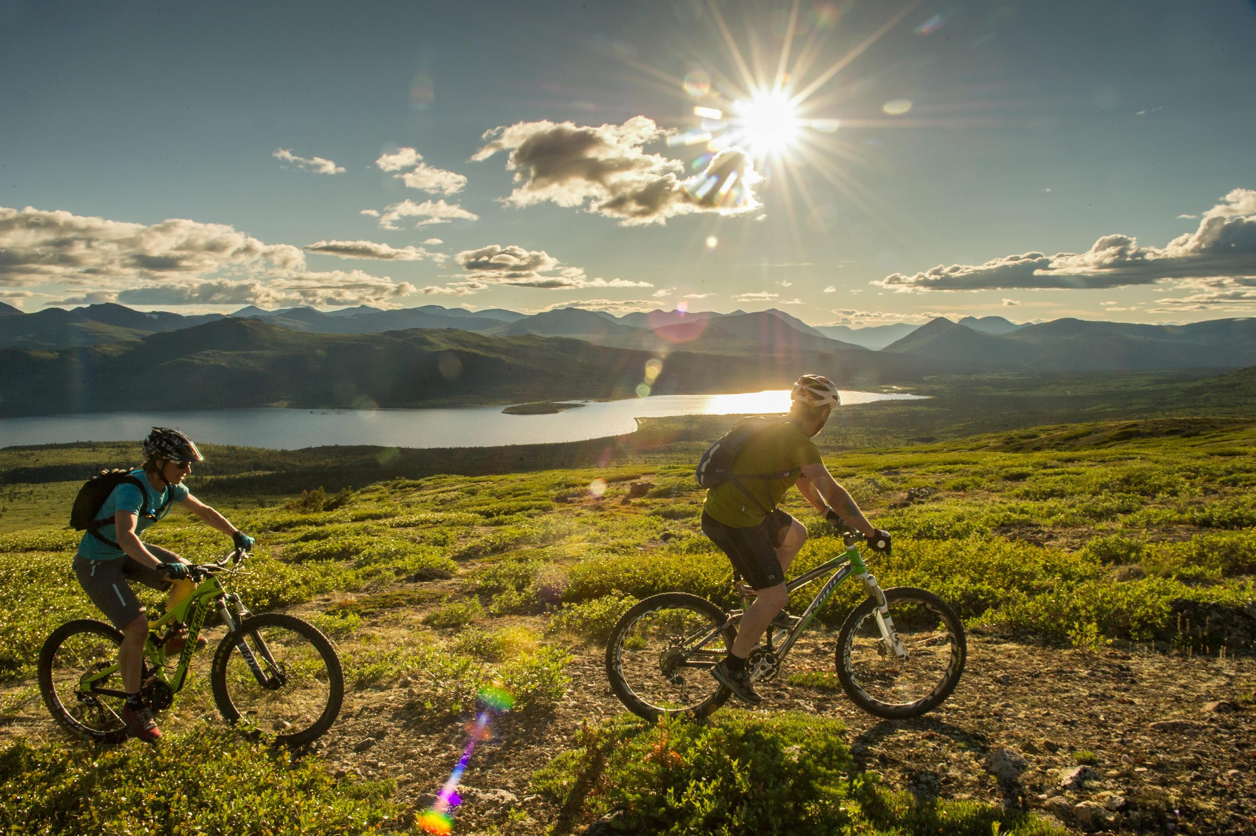 Deux personnes faisant du VTT devant une montagne et un lac. Deux personnes faisant du VTT devant une montagne et un lac.