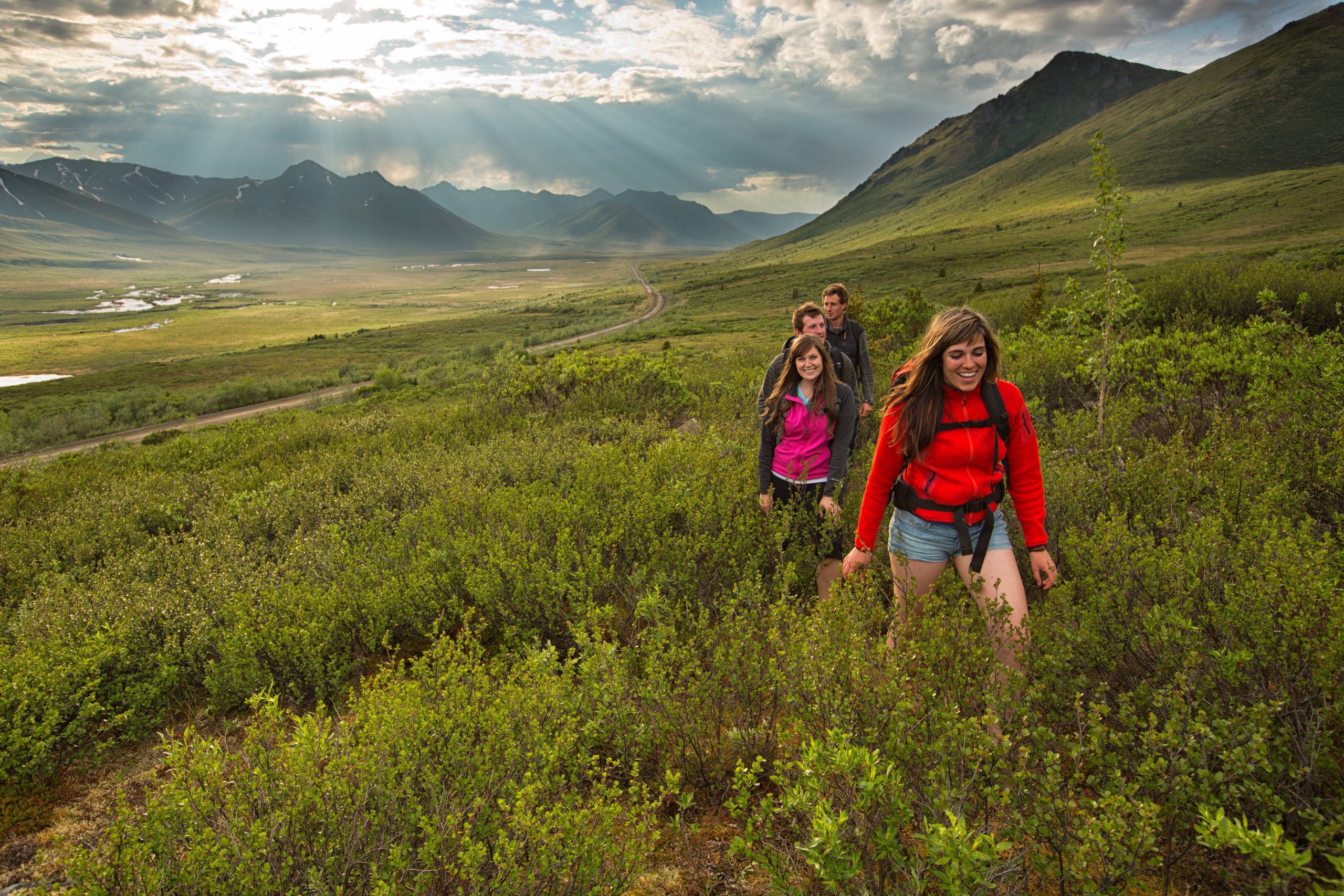 A group of people hiking in a field surrounded by mountains. A group of people hiking in a field surrounded by mountains.