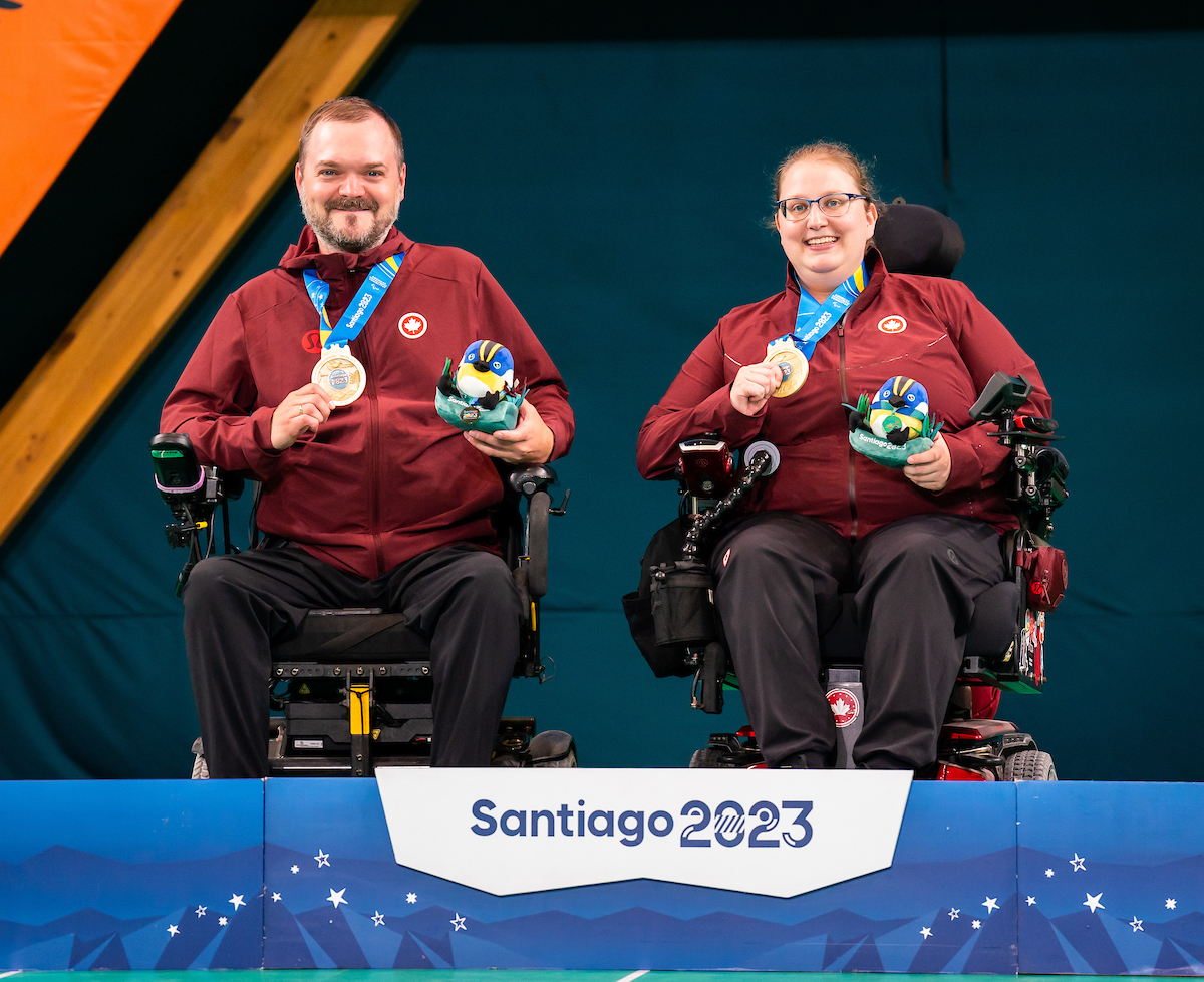 Iulian Ciobanu and Alison Levine talking standing on a podium and holding gold medals. Iulian Ciobanu and Alison Levine talking standing on a podium and holding gold medals.