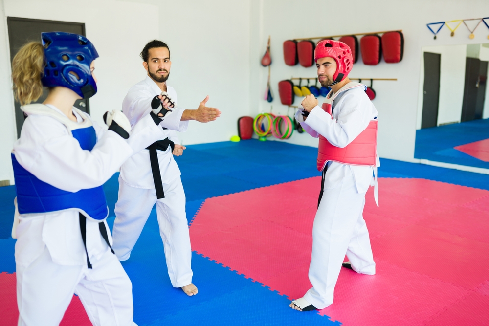 Deux athlètes de taekwondo qui s’affrontent et un arbitre. Deux athlètes de taekwondo qui s’affrontent et un arbitre.