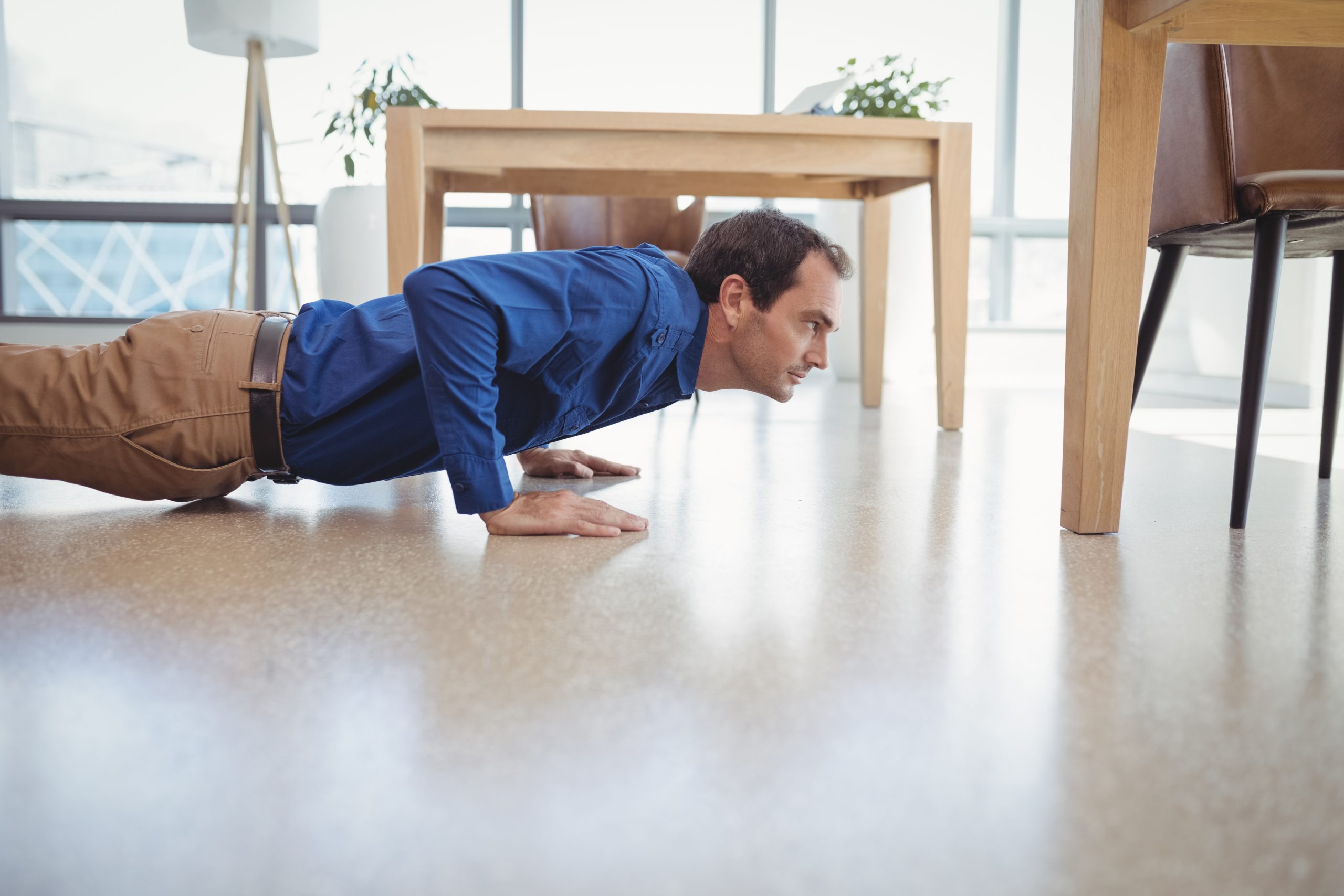 Un homme fait des pompes sur le sol de son bureau. Un homme fait des pompes sur le sol de son bureau.