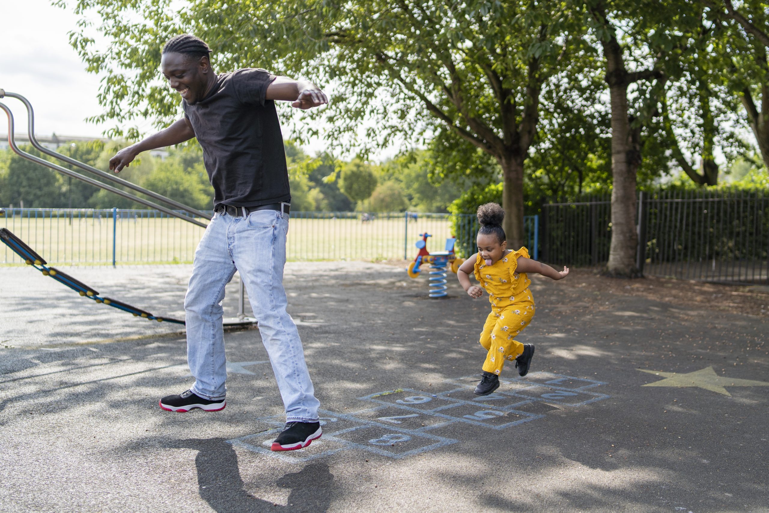 A father and daughter playing hopscotch at a playground. A father and daughter playing hopscotch at a playground.