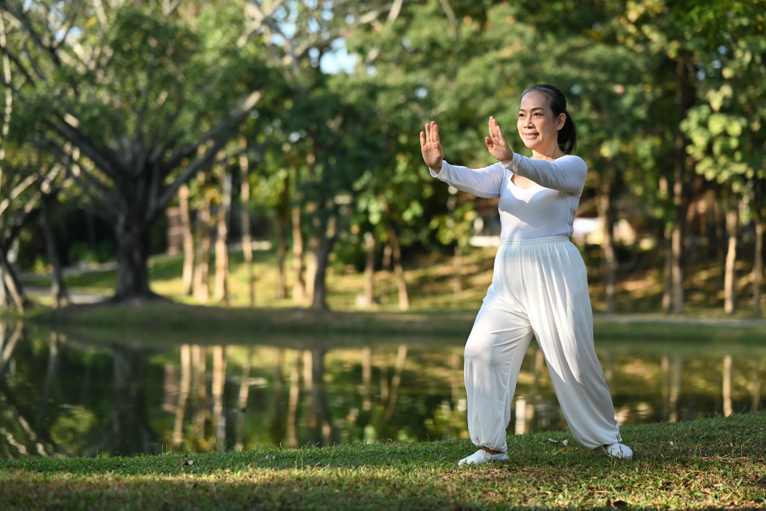 Une femme pratique le tai-chi près d’un étang. Une femme pratique le tai-chi près d’un étang.
