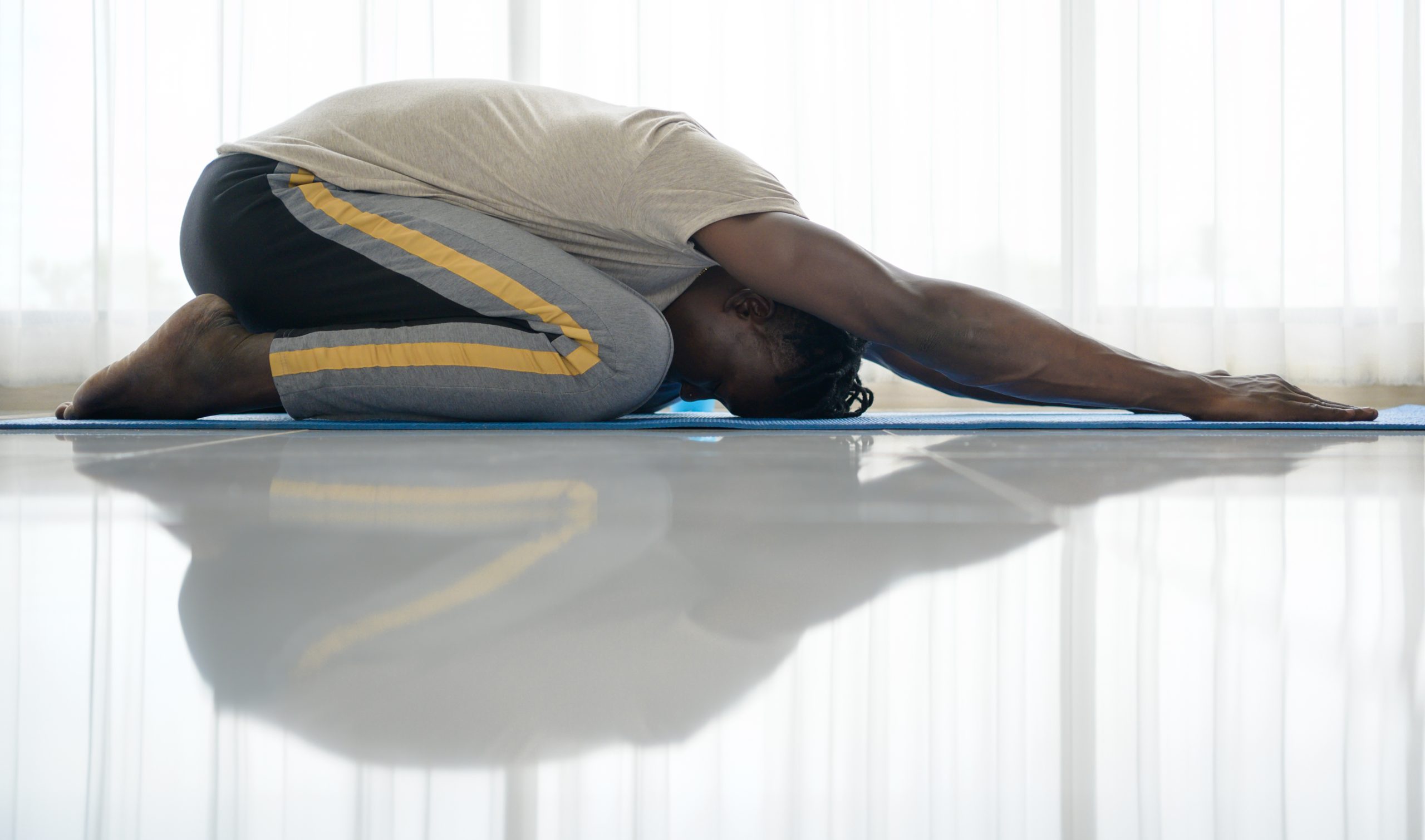 Un homme effectue la posture de l’enfant en yoga. Un homme effectue la posture de l’enfant en yoga.