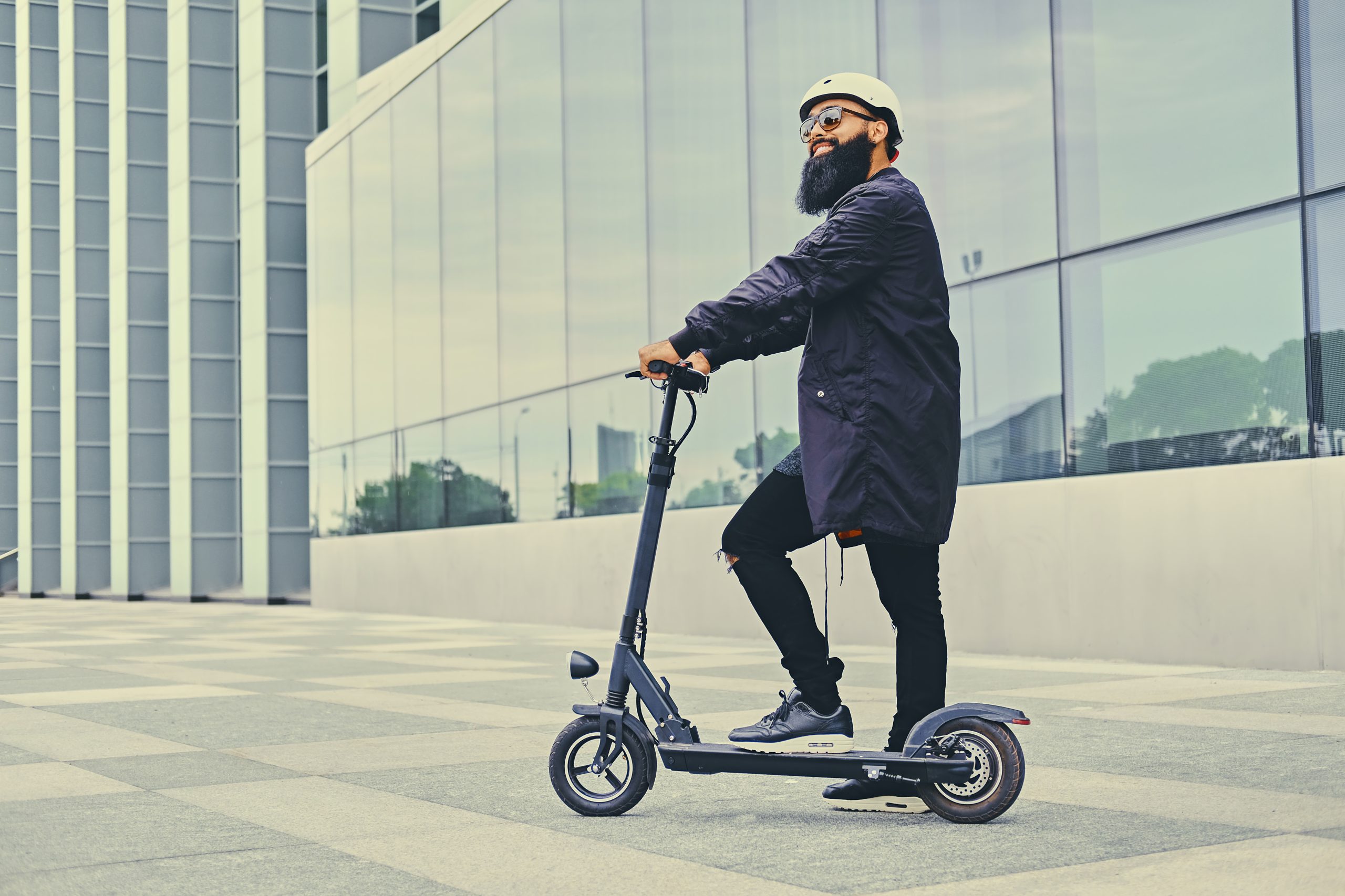 Un homme sur une trottinette électrique devant un immeuble. Un homme sur une trottinette électrique devant un immeuble.
