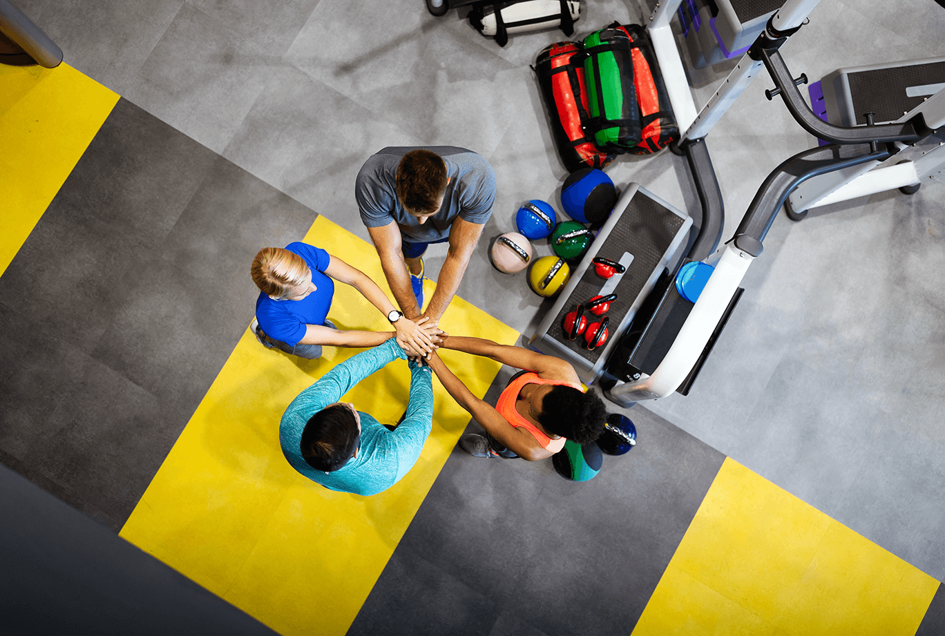 A group of people holding hands together in a gym. A group of people holding hands together in a gym.