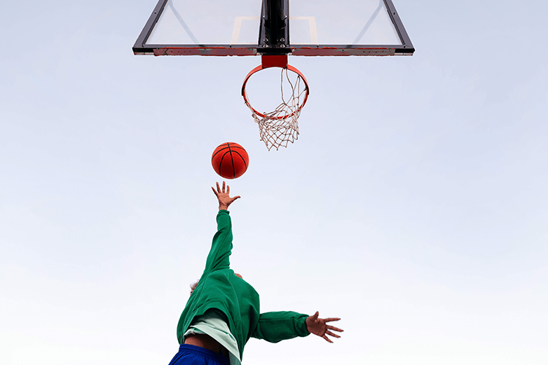 A person shooting a basketball into a basketball net. A person shooting a basketball into a basketball net.