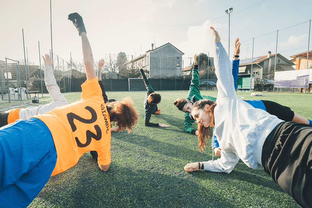 Football players in a side plank position on the pitch Football players in a side plank position on the pitch