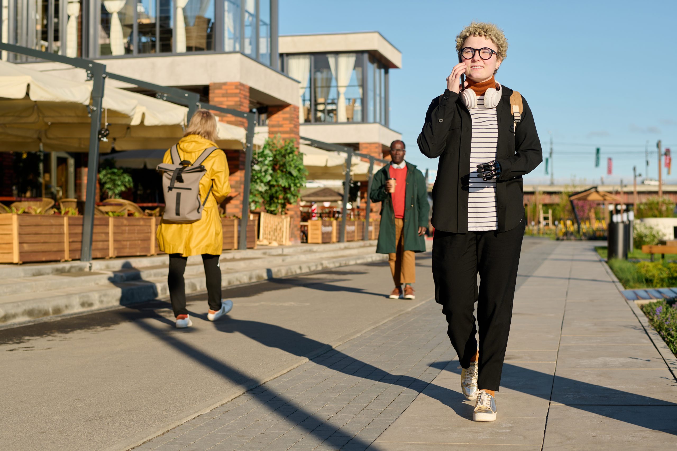 Three people walking on a sidewalk. Three people walking on a sidewalk.