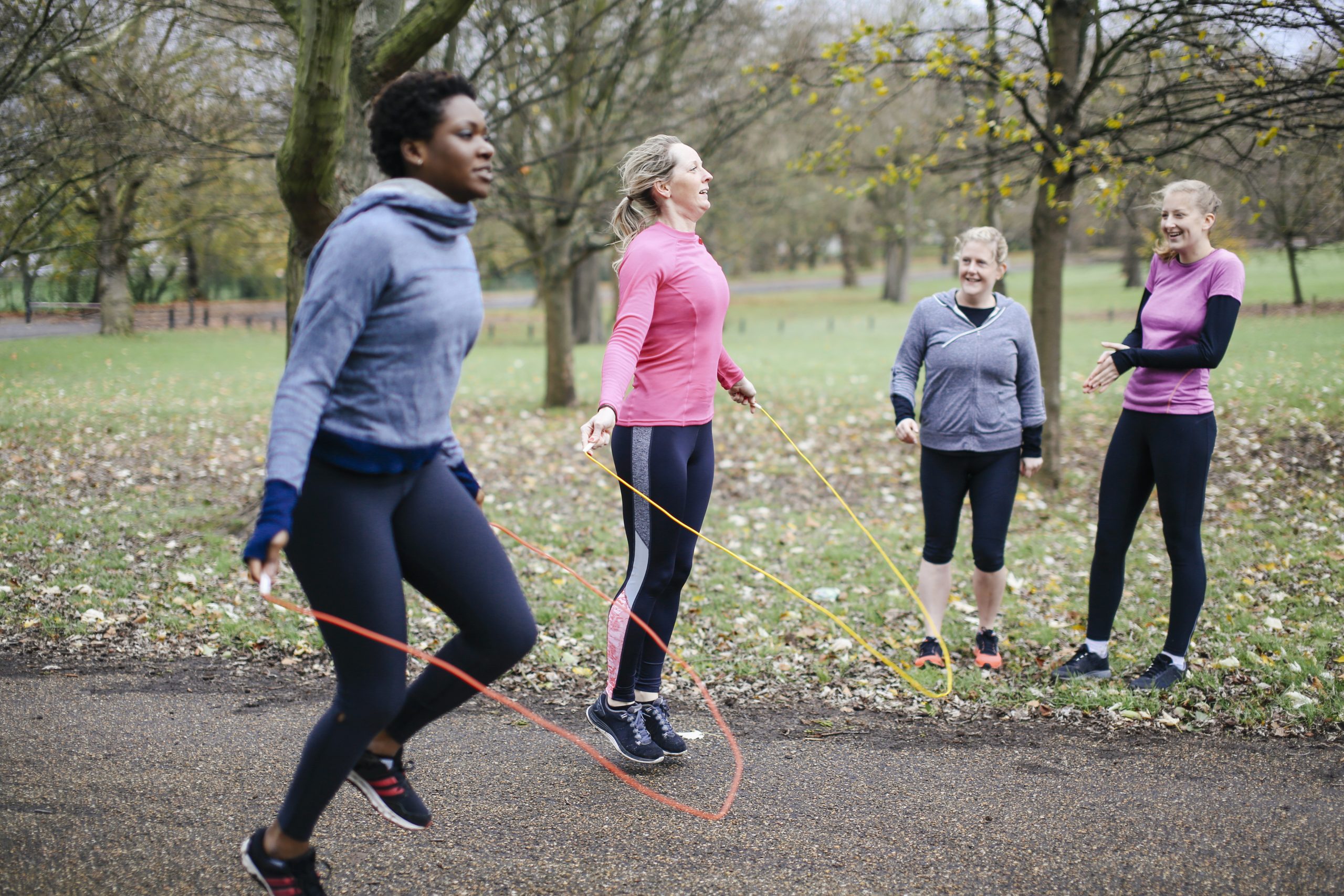 A group of people jumping rope in a park. A group of people jumping rope in a park.