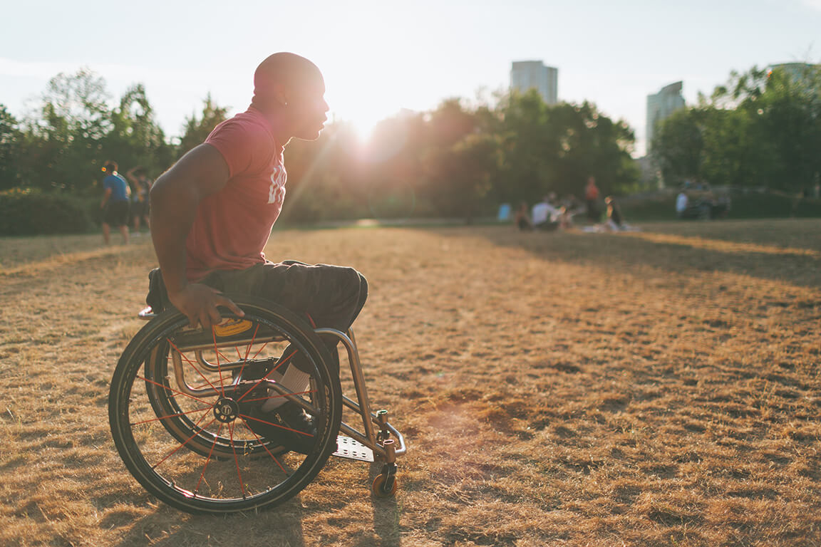 Un homme en fauteuil roulant sur un terrain dans un parc. Un homme en fauteuil roulant sur un terrain dans un parc.