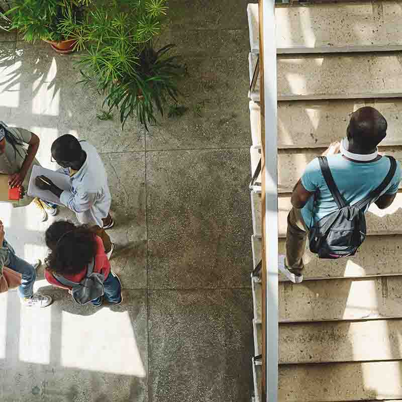 overhead view of a student climbing stairs, and students in an open room overhead view of a student climbing stairs, and students in an open room