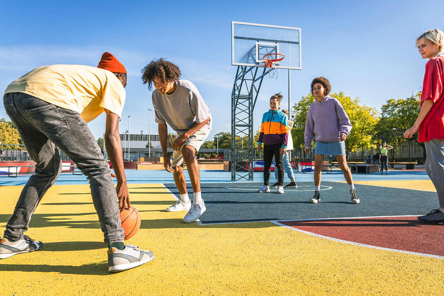 A group of teens playing a game of basketball together A group of teens playing a game of basketball together