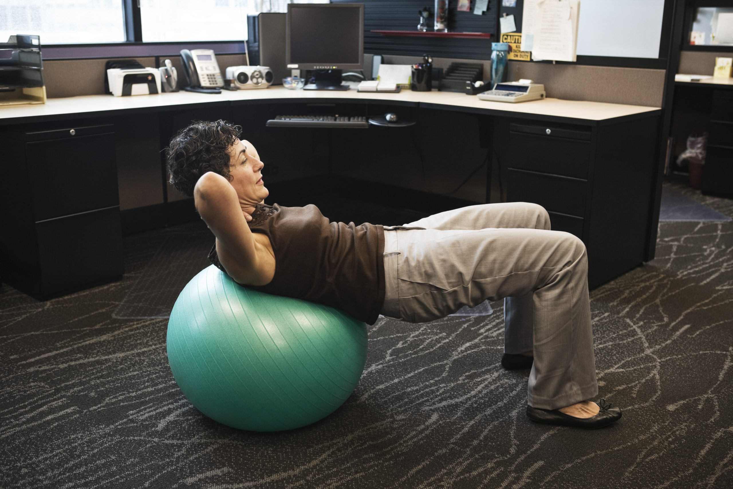 Une femme exécute des redressements assis sur un ballon d’exercice dans un bureau. Une femme exécute des redressements assis sur un ballon d’exercice dans un bureau.