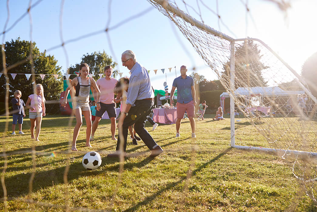 A multi-generational group playing soccer together at a community gathering A multi-generational group playing soccer together at a community gathering