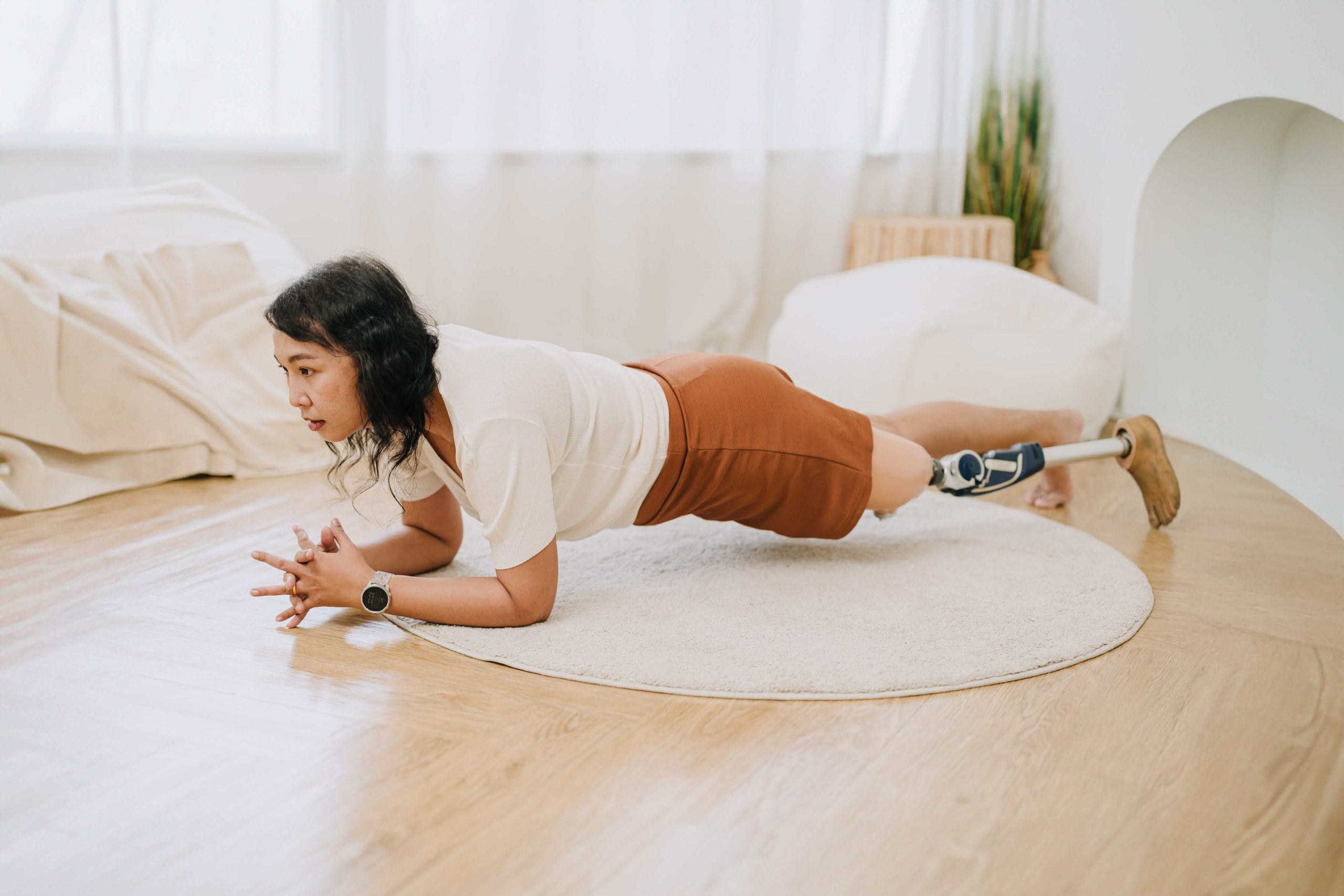 Une femme avec une prothèse de jambe effectue une planche dans un salon. Une femme avec une prothèse de jambe effectue une planche dans un salon.