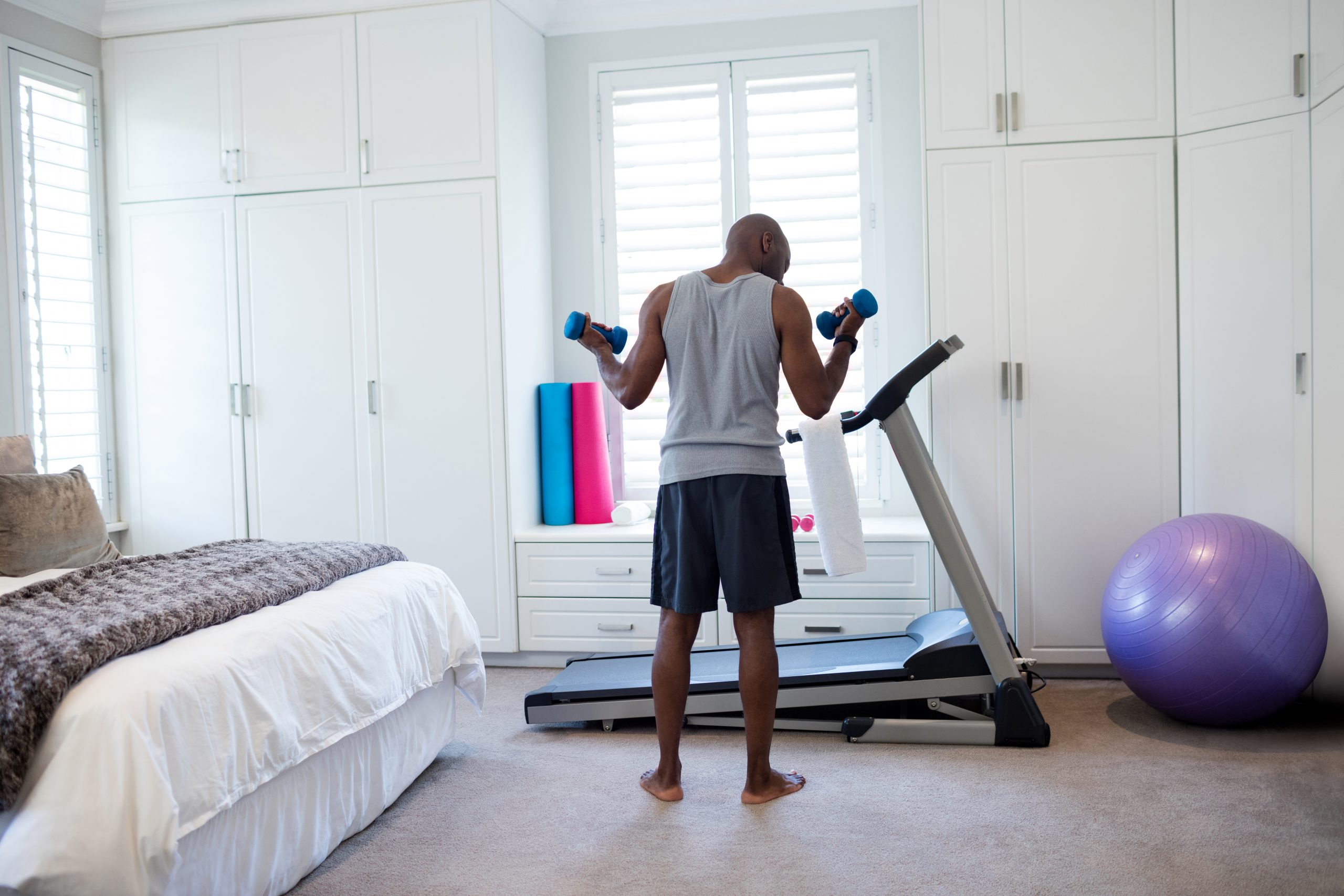 A man lifting dumbbells in a bedroom. A man lifting dumbbells in a bedroom.