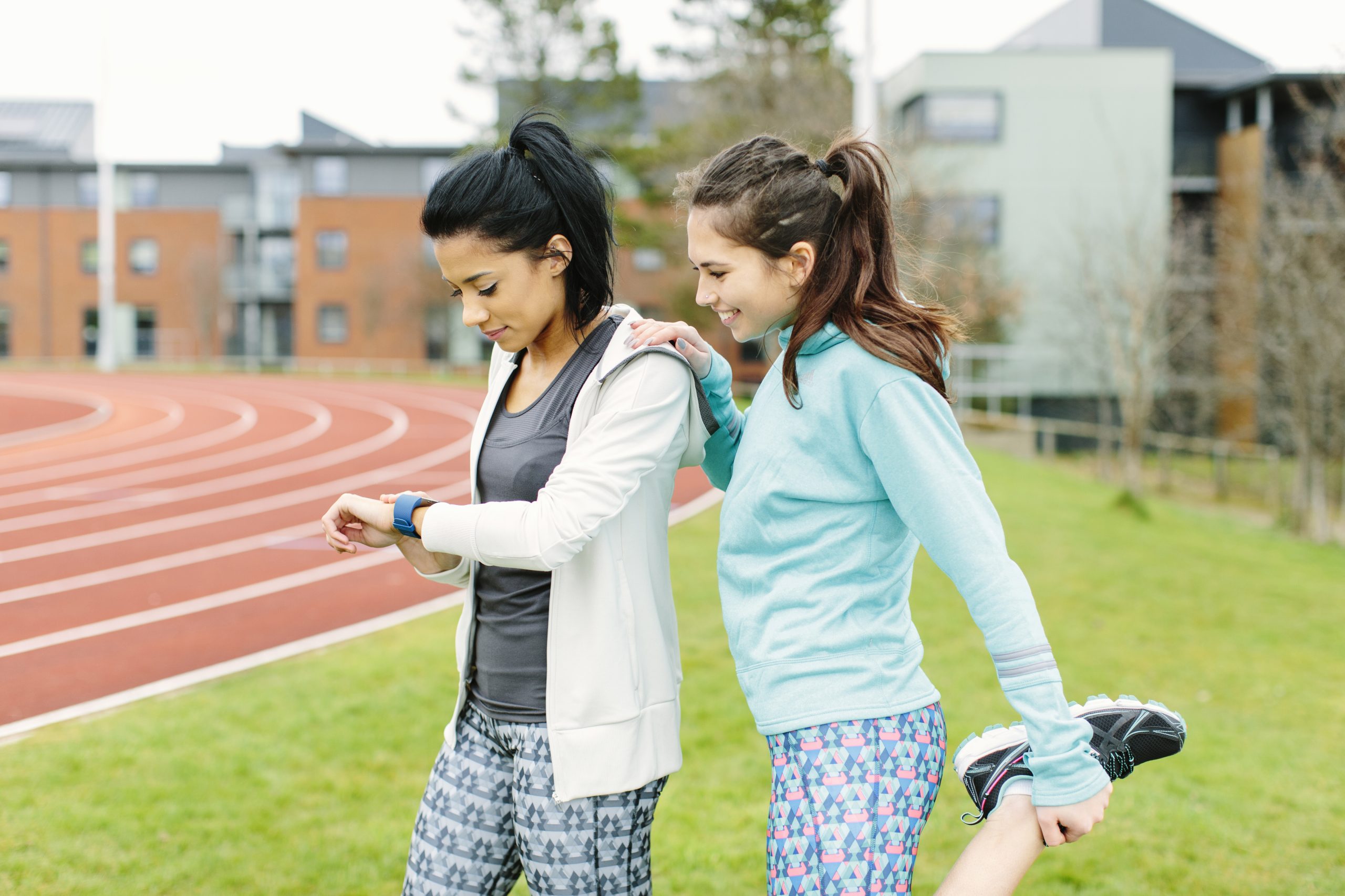 Deux femmes consultent un moniteur d’activités près d’une piste d’athlétisme extérieure. Deux femmes consultent un moniteur d’activités près d’une piste d’athlétisme extérieure.