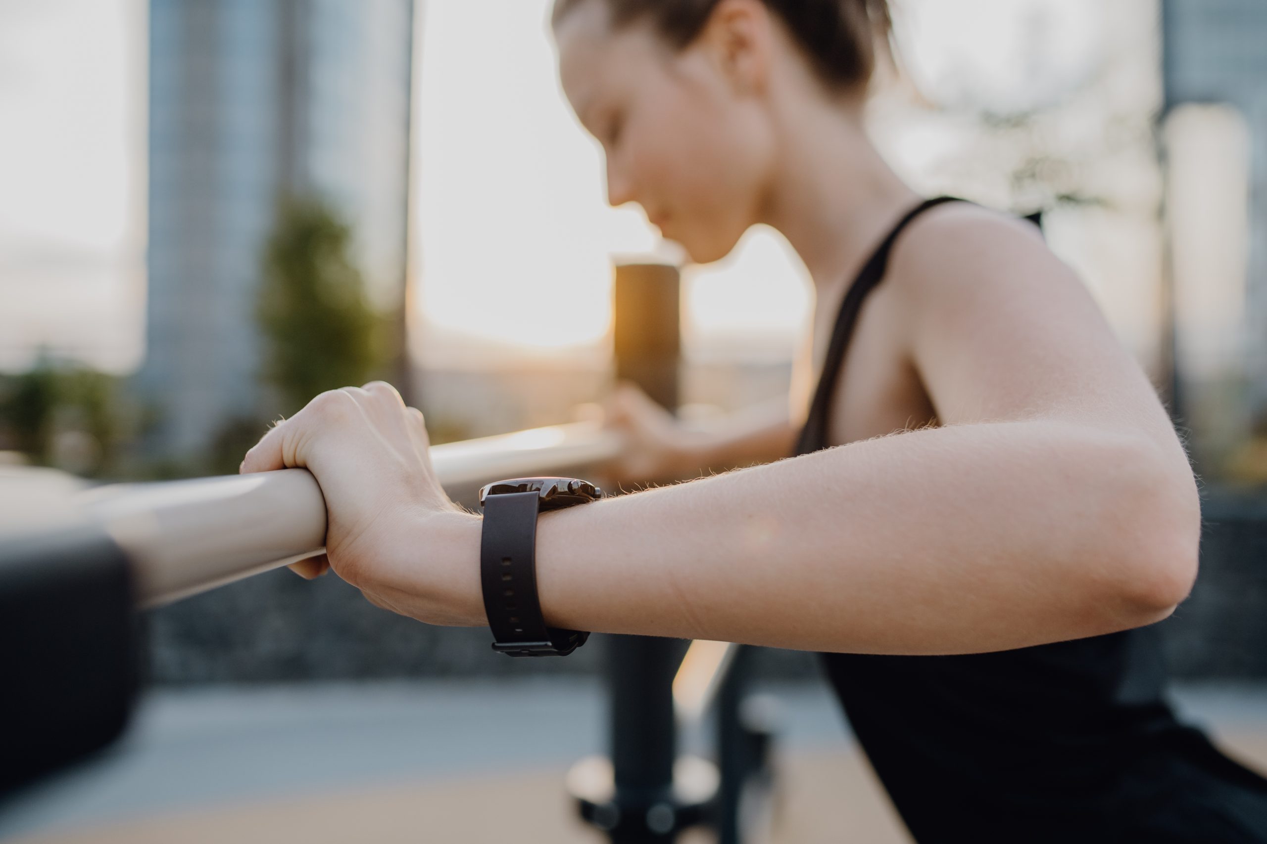 A woman wearing a fitness tracker on her wrist while doing push-ups on a bar. A woman wearing a fitness tracker on her wrist while doing push-ups on a bar.