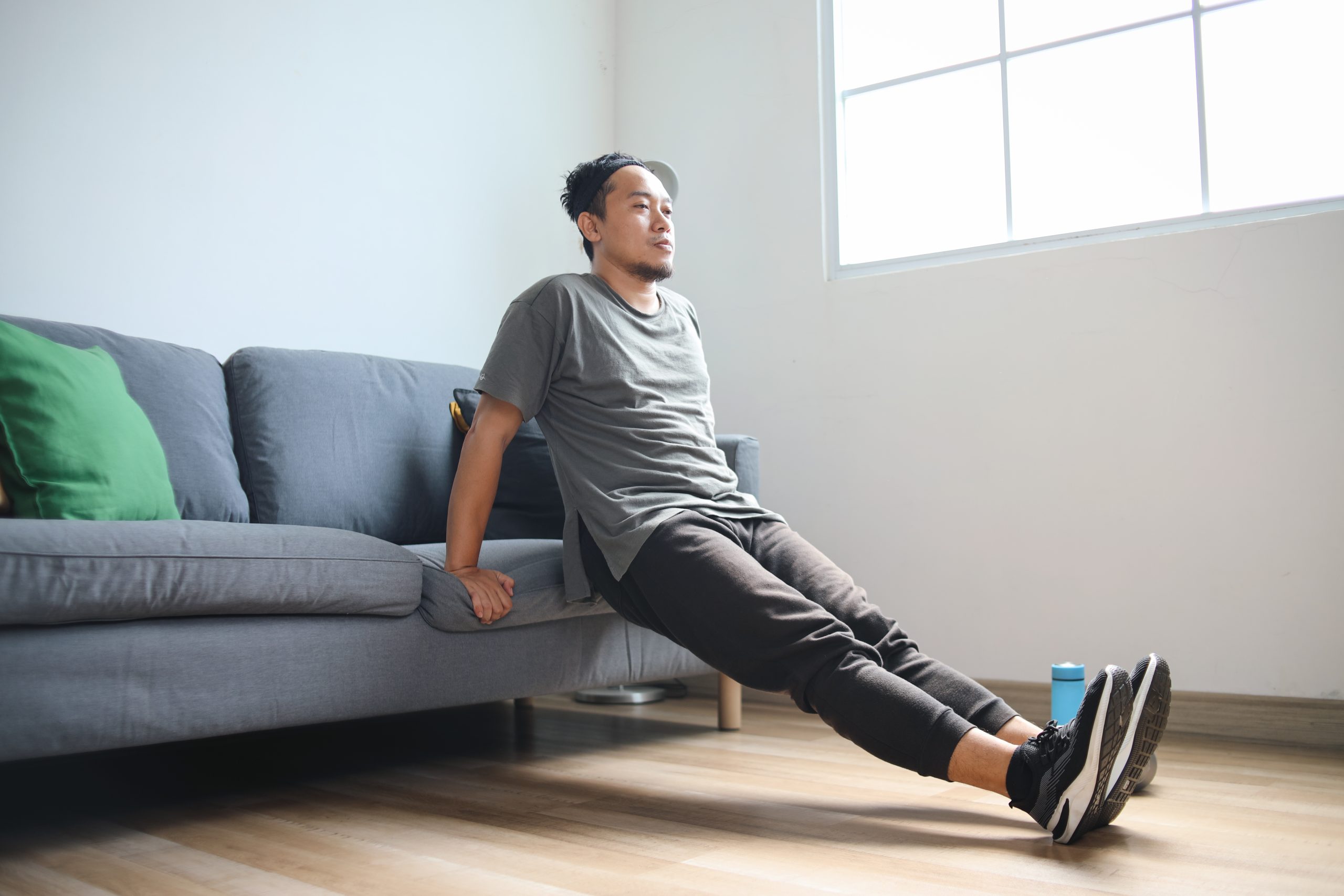 A man doing triceps dips at the edge of a couch. A man doing triceps dips at the edge of a couch.