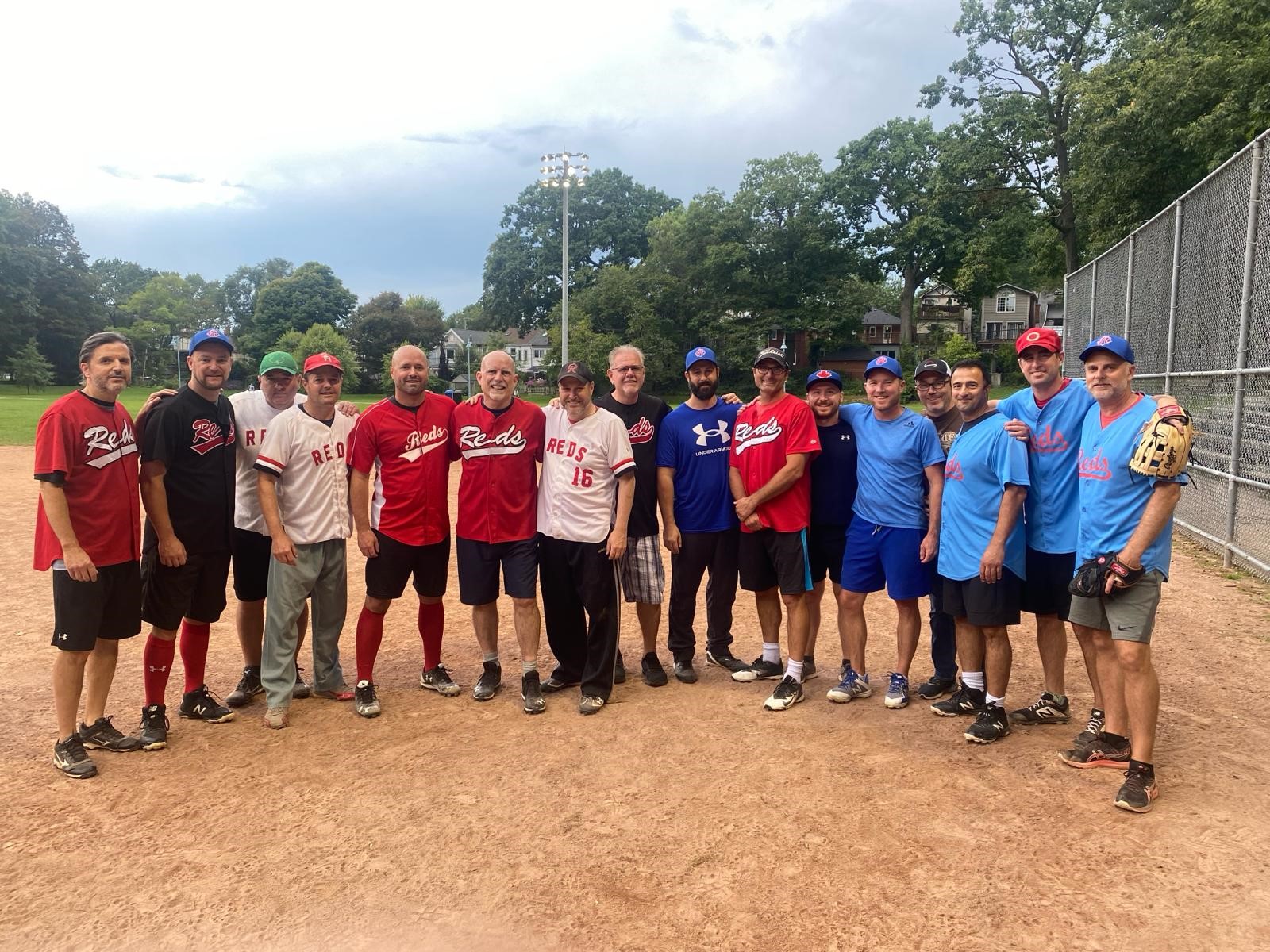 A group of male softball players standing on a softball diamond. A group of male softball players standing on a softball diamond.