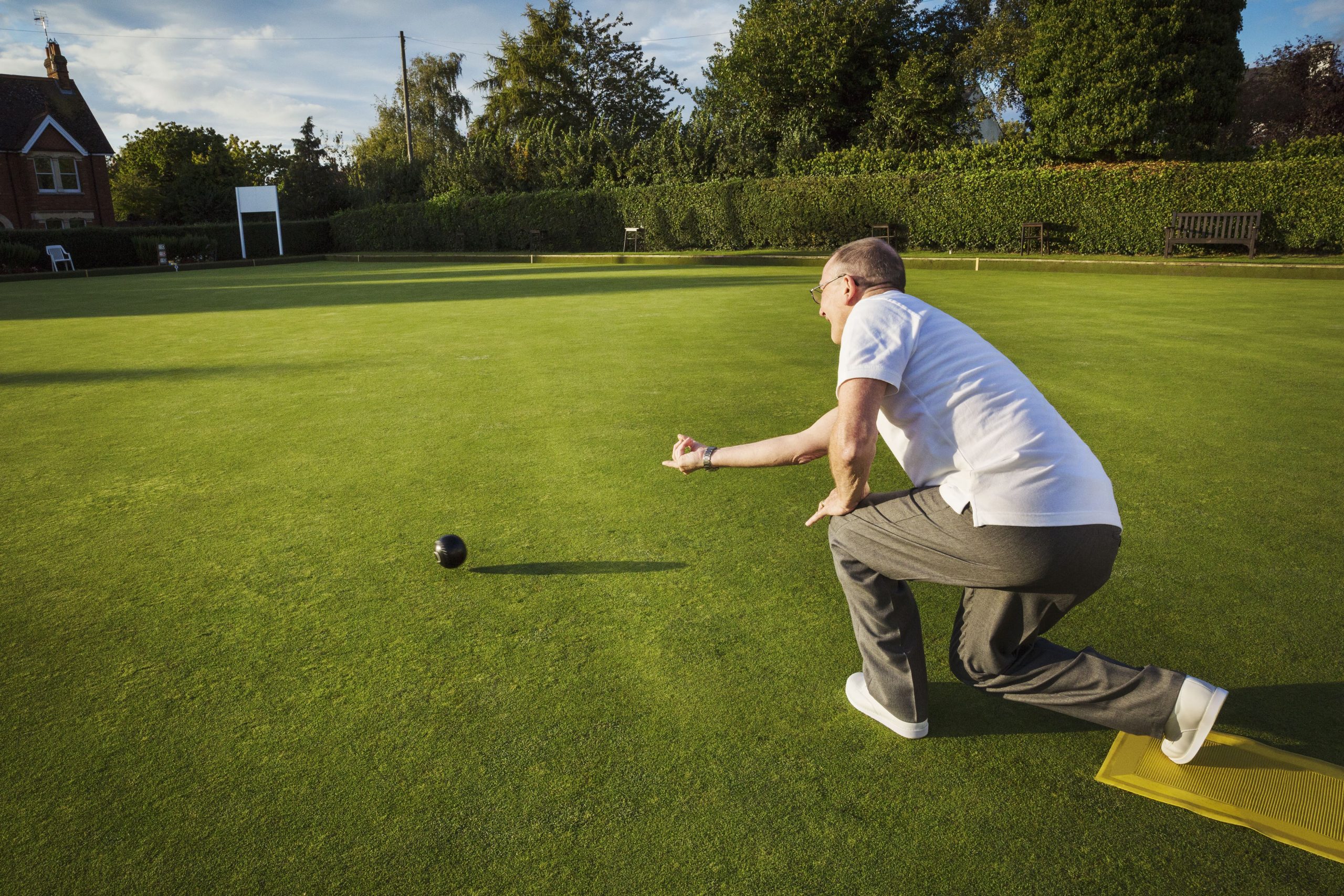 A man rolling a bowl on a green. A man rolling a bowl on a green.