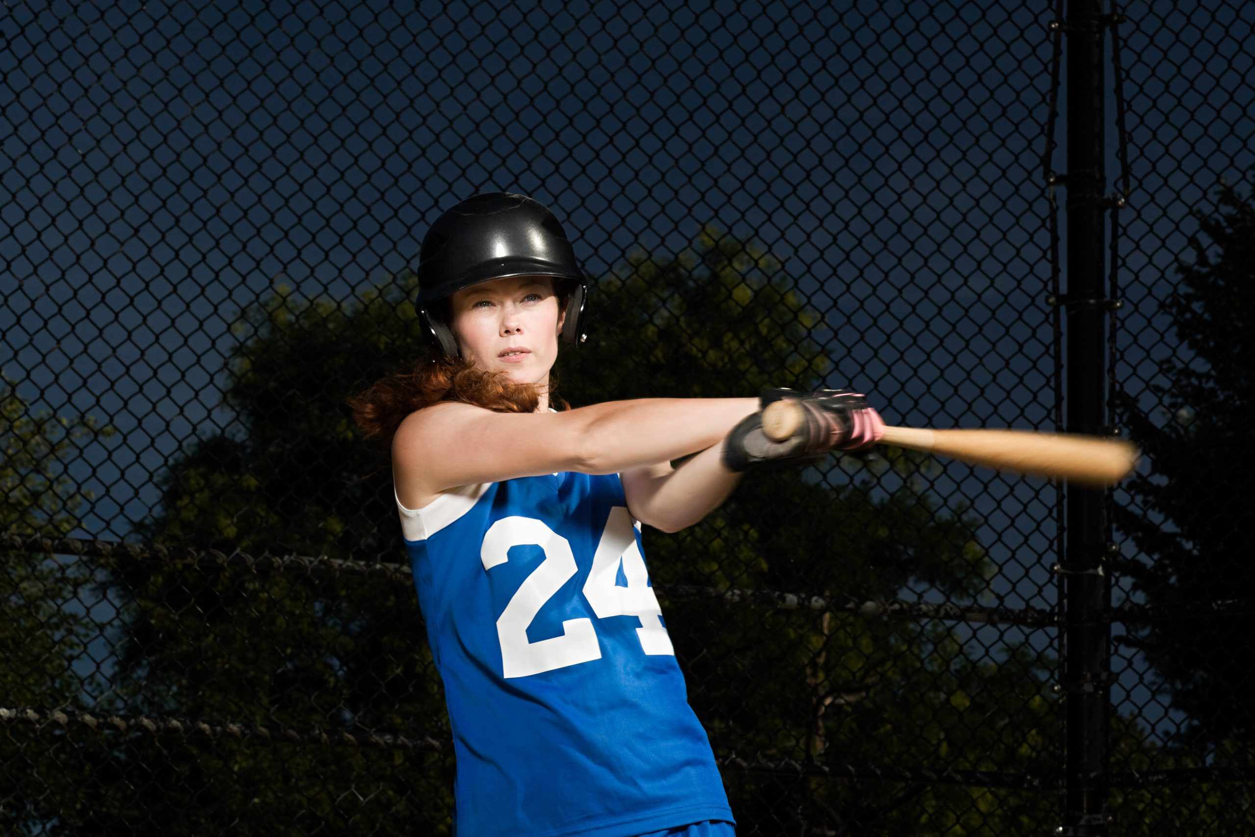 A woman swinging a softball bat. A woman swinging a softball bat.