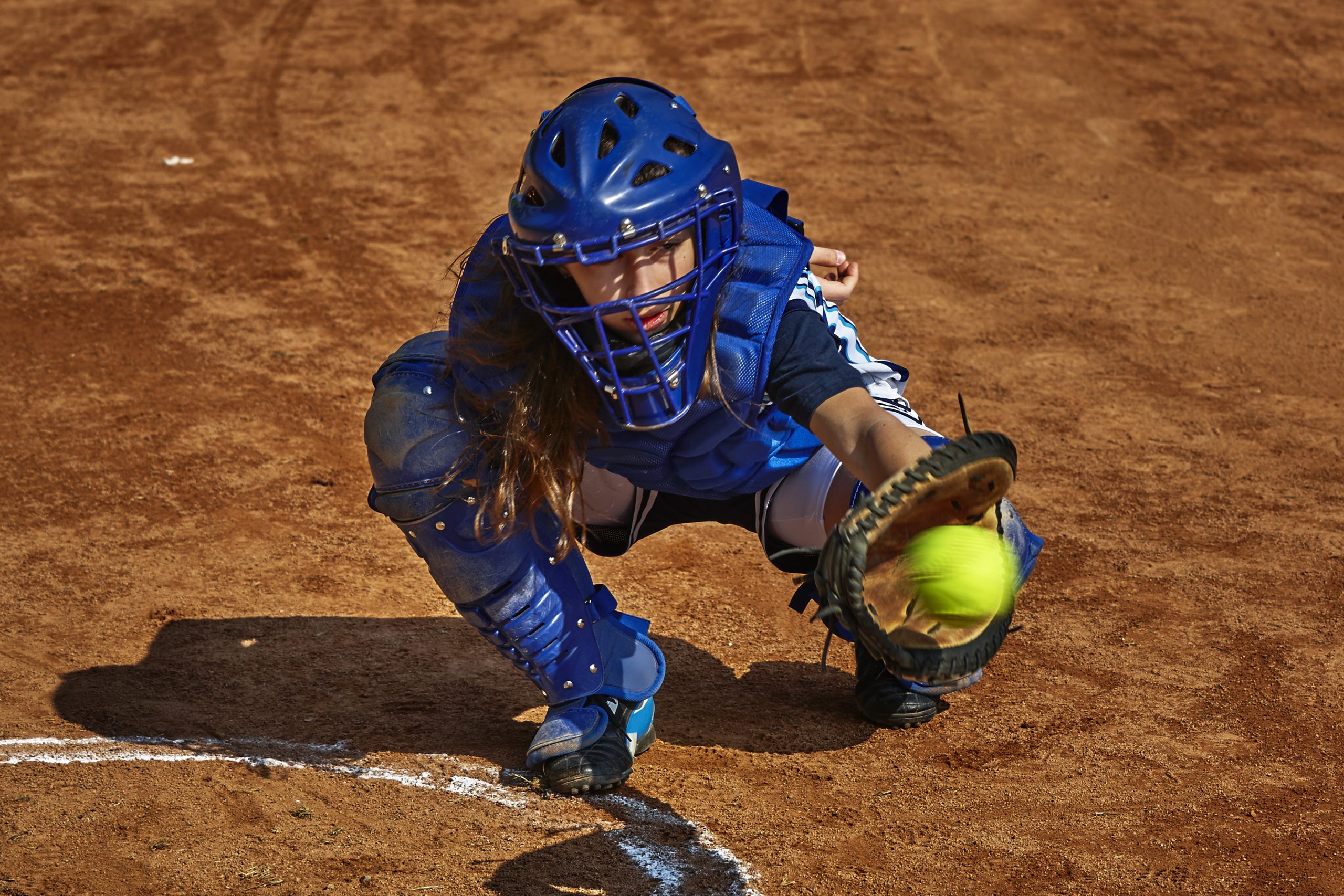 A softball player catching a softball using a softball glove. A softball player catching a softball using a softball glove.