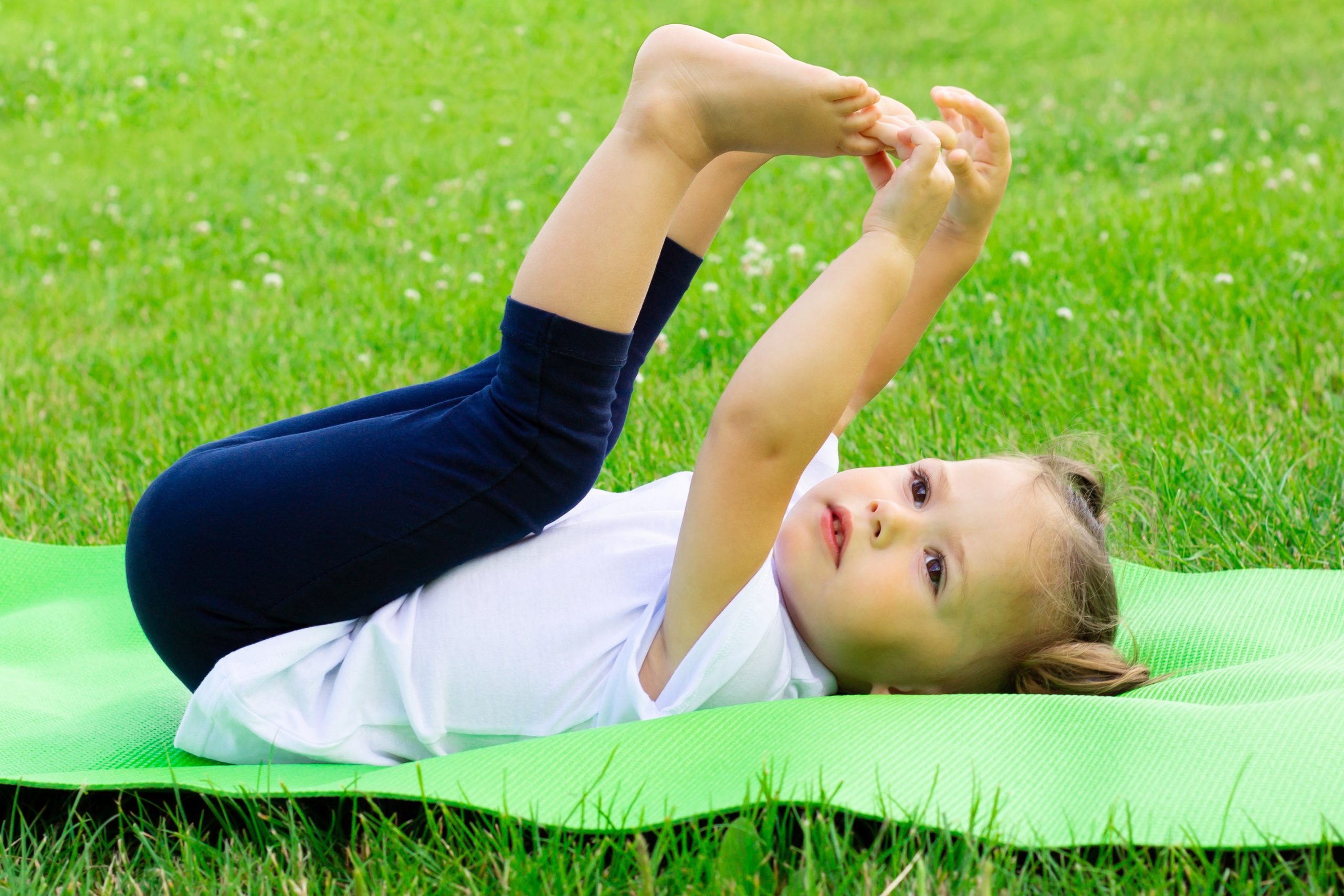 Une jeune fille s’étire sur un tapis de yoga dans un champ. Une jeune fille s’étire sur un tapis de yoga dans un champ.