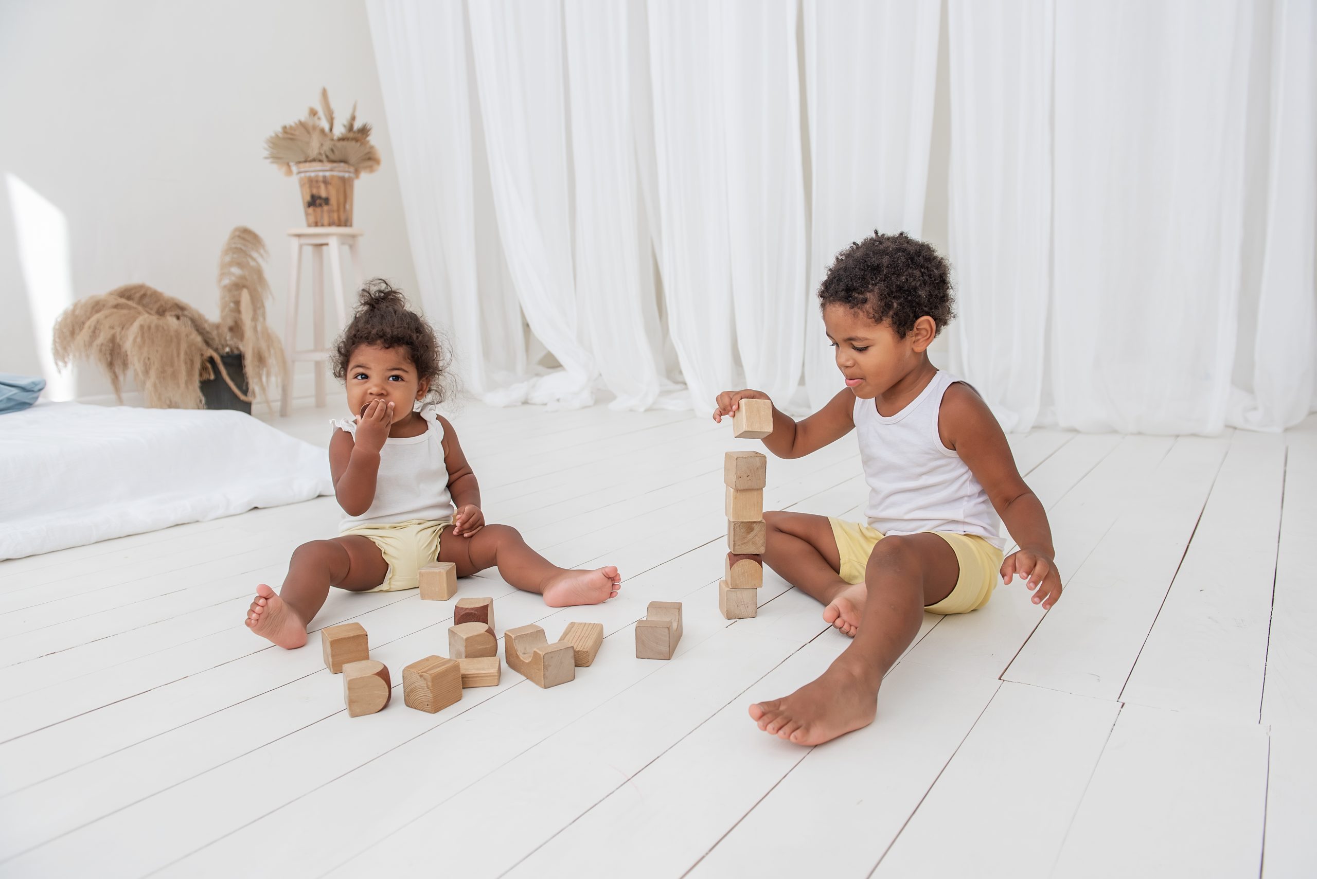 Deux jeunes enfants jouent avec des blocs de bois sur le plancher d’une chambre. Deux jeunes enfants jouent avec des blocs de bois sur le plancher d’une chambre.